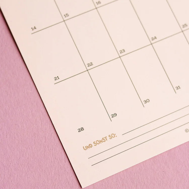 Nahaufnahme eines Kalenderblattes mit leeren Datumsfeldern auf einer rosa Fläche. Am unteren Rand sind die deutschen Worte UND SONST SO: in goldener Schrift gedruckt.