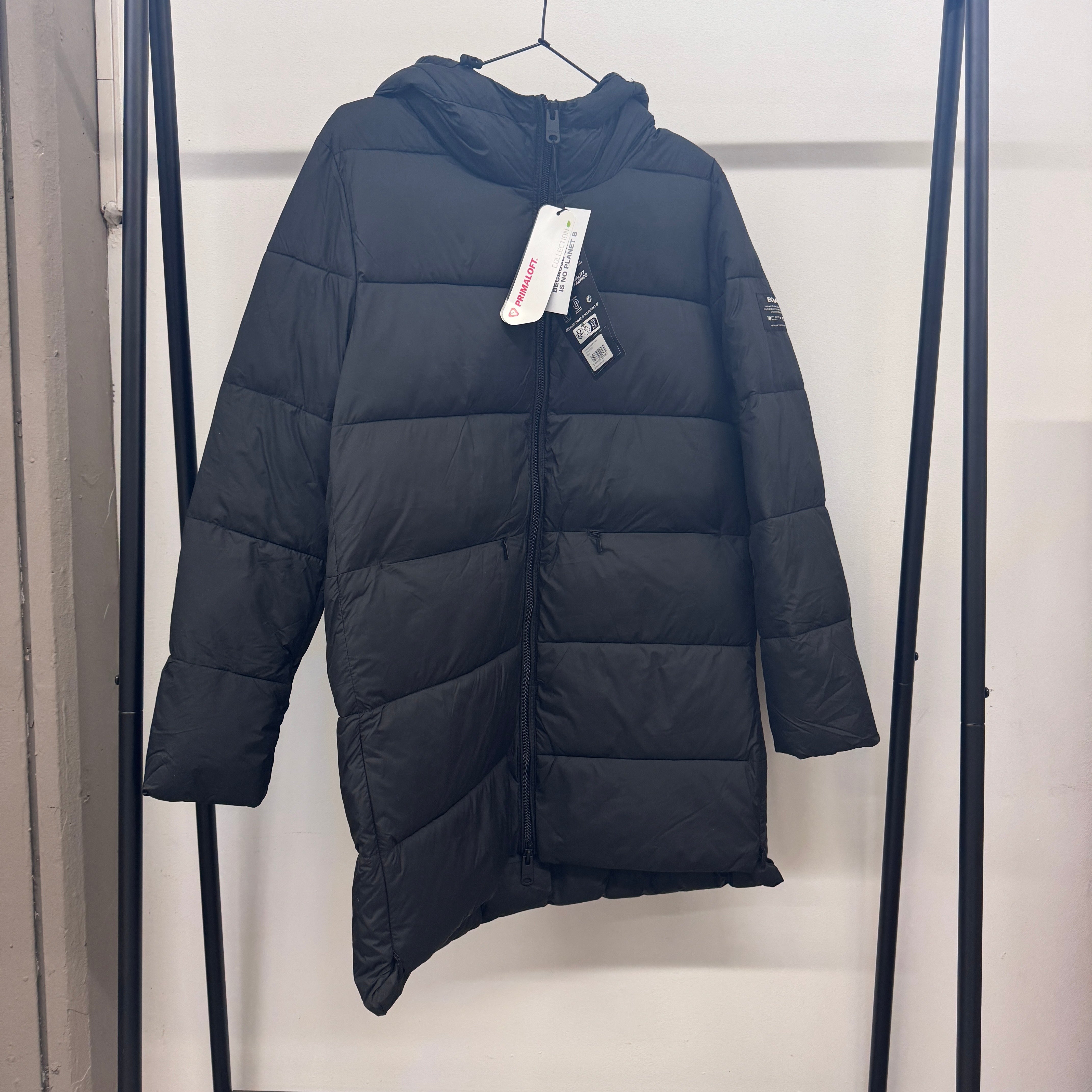 Schwarzer, gesteppter Wintermantel mit Kapuze hängt an einem Kleiderständer.