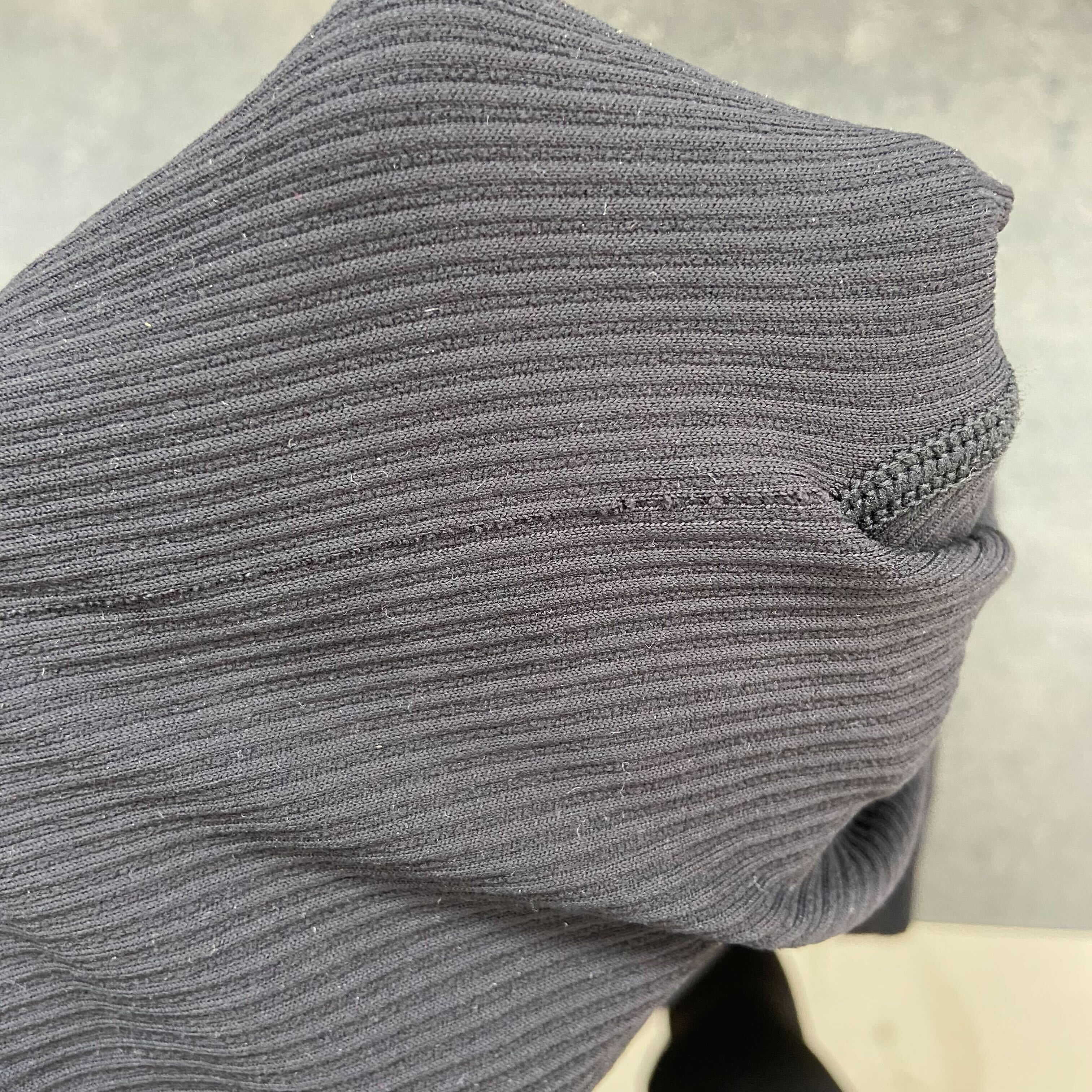 Nahaufnahme eines dunkelgrauen, gerippten Stoffstücks mit sichtbarer Naht.
