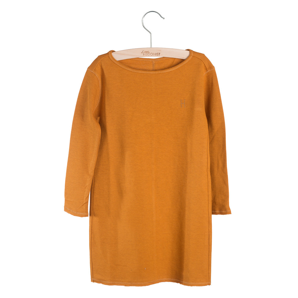 Ein langärmeliges, orange-braunes Kleid für Kinder hängt auf einem Holzbügel vor einem weißen Hintergrund. Das Kleid hat ein einfaches Design mit rundem Halsausschnitt und einem kleinen aufgestickten H auf der Brust.