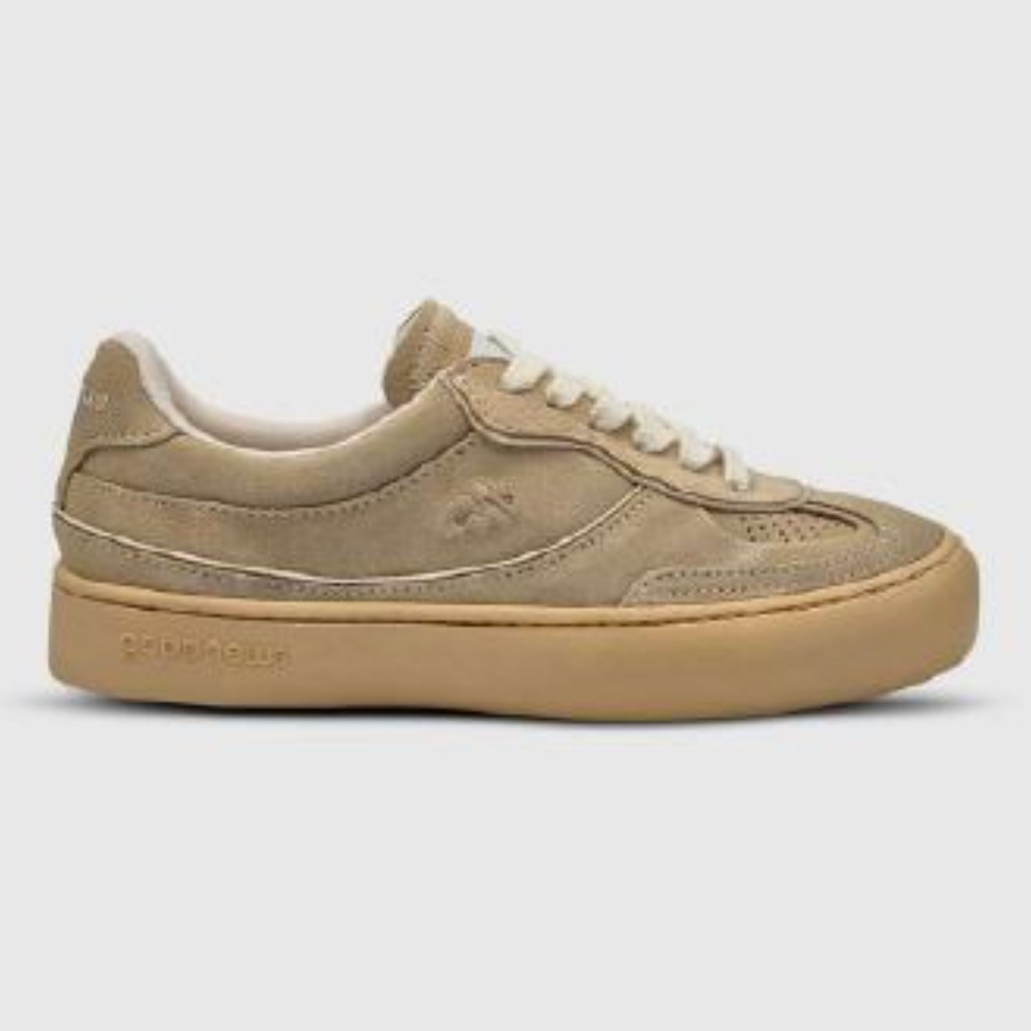 Ein beiger Wildleder-Sneaker mit weißen Schnürsenkeln, dezenten Nähten und einer dicken hellbraunen Gummisohle auf einem schlichten grauen Hintergrund.