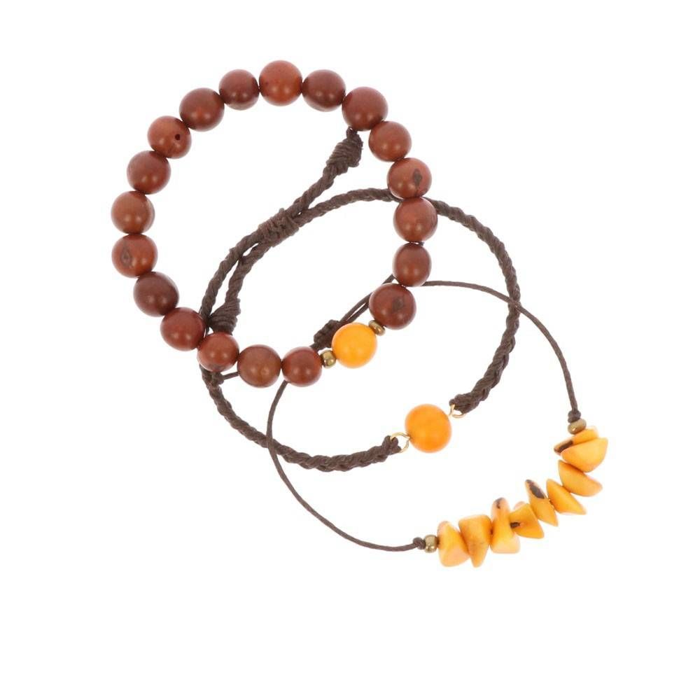 Drei braune Kordelarmbänder: eines mit großen runden Holzperlen, eines mit einer einzelnen runden gelben Perle und eines mit mehreren kleinen gelben unregelmäßigen Perlen.