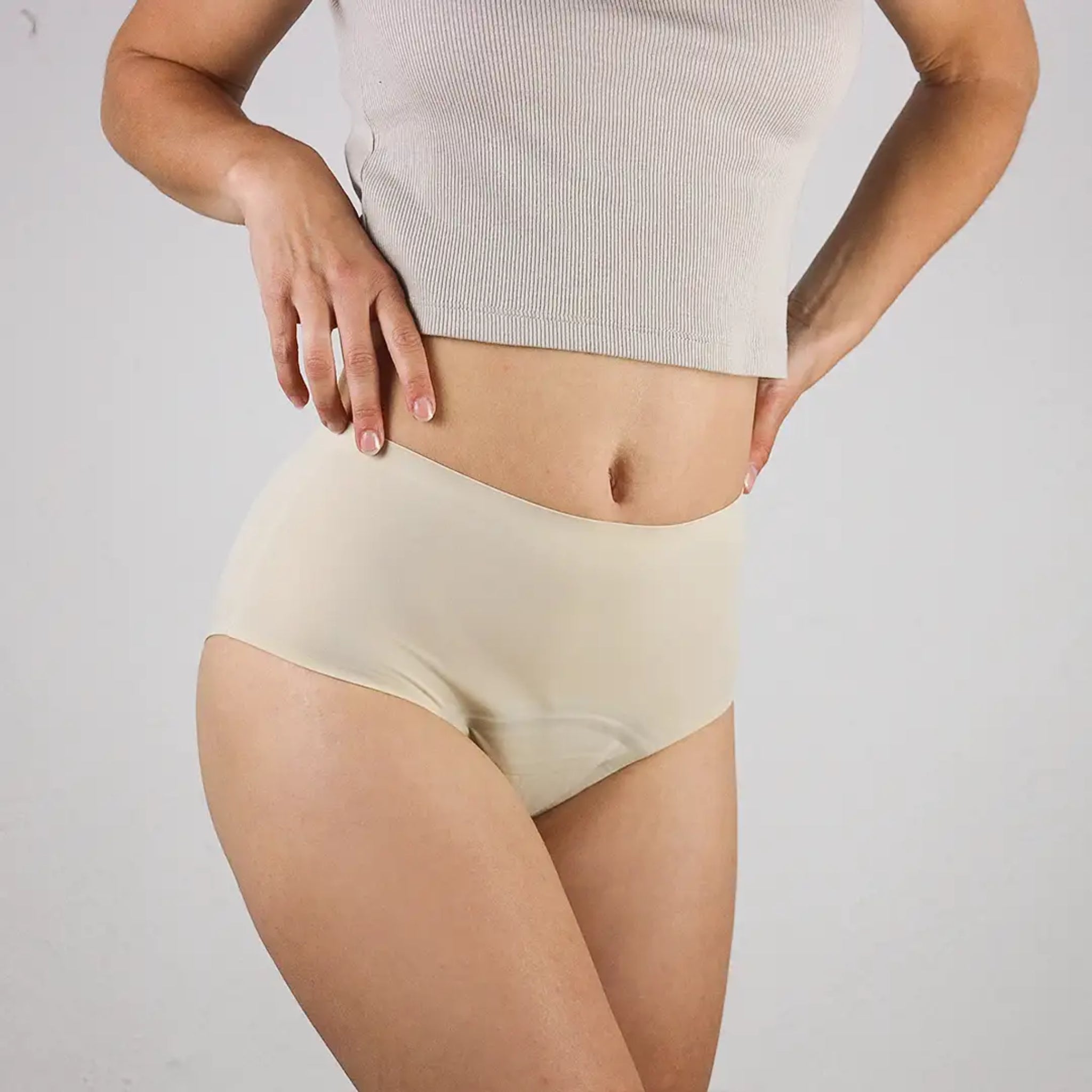 Eine Person trägt einen beigefarbenen Slip und ein kurzes, geripptes, graues Oberteil.