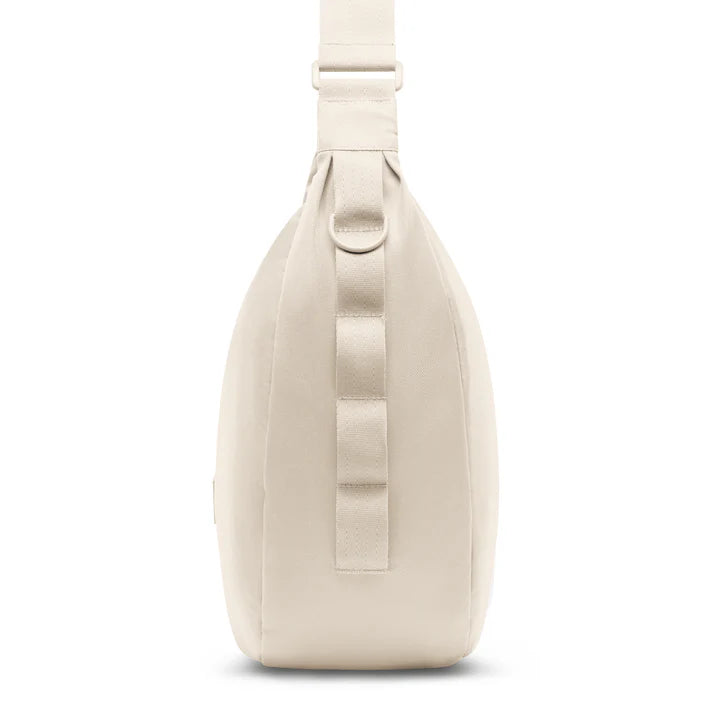 Eine Seitenansicht einer hellbeigen Crossbody-Tasche mit breitem, verstellbarem Riemen und minimalistischem Design, das durch vertikale Schlaufen an der Seite zusätzliche Funktionalität bietet.