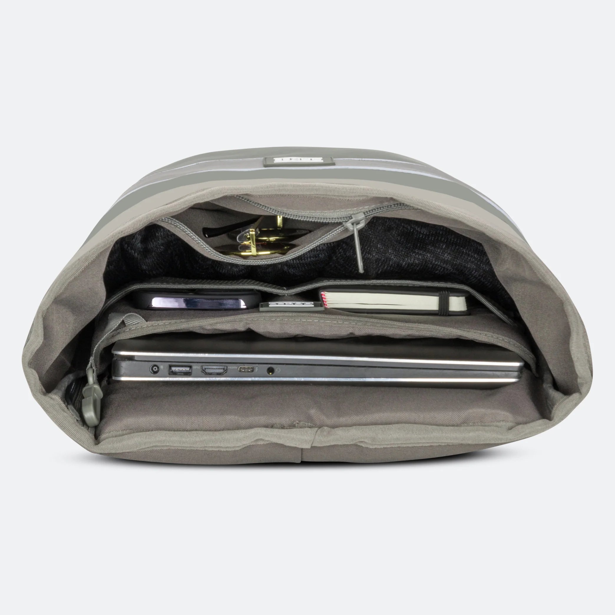 Ein grauer Rucksack öffnete sich und zeigte geordnete Fächer, in denen sich ein Laptop, ein Notebook, ein Telefon, Stifte und eine kleine Tasche befanden.