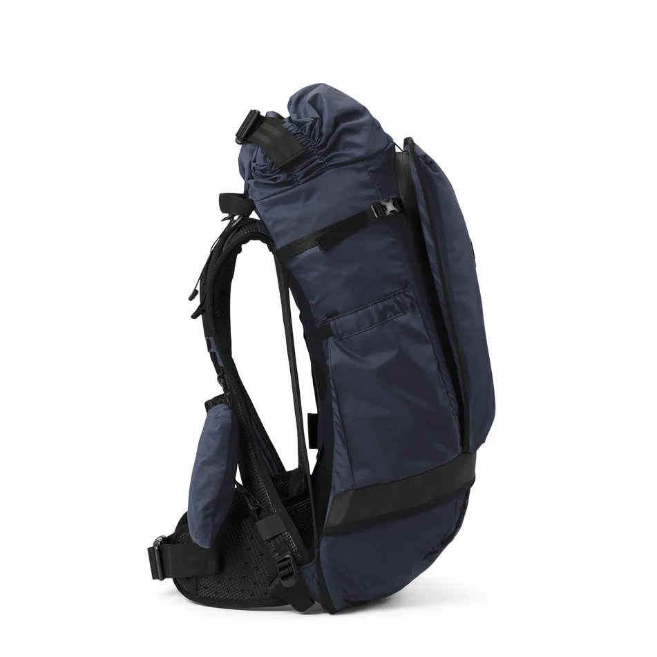 Seitenansicht eines dunkelblauen Wanderrucksacks mit gepolsterten Schultergurten, einem Hüftgurt, einer Netzrückwand und mehreren Taschen. Der Rucksack scheint strukturiert und für den Einsatz im Freien geeignet zu sein.