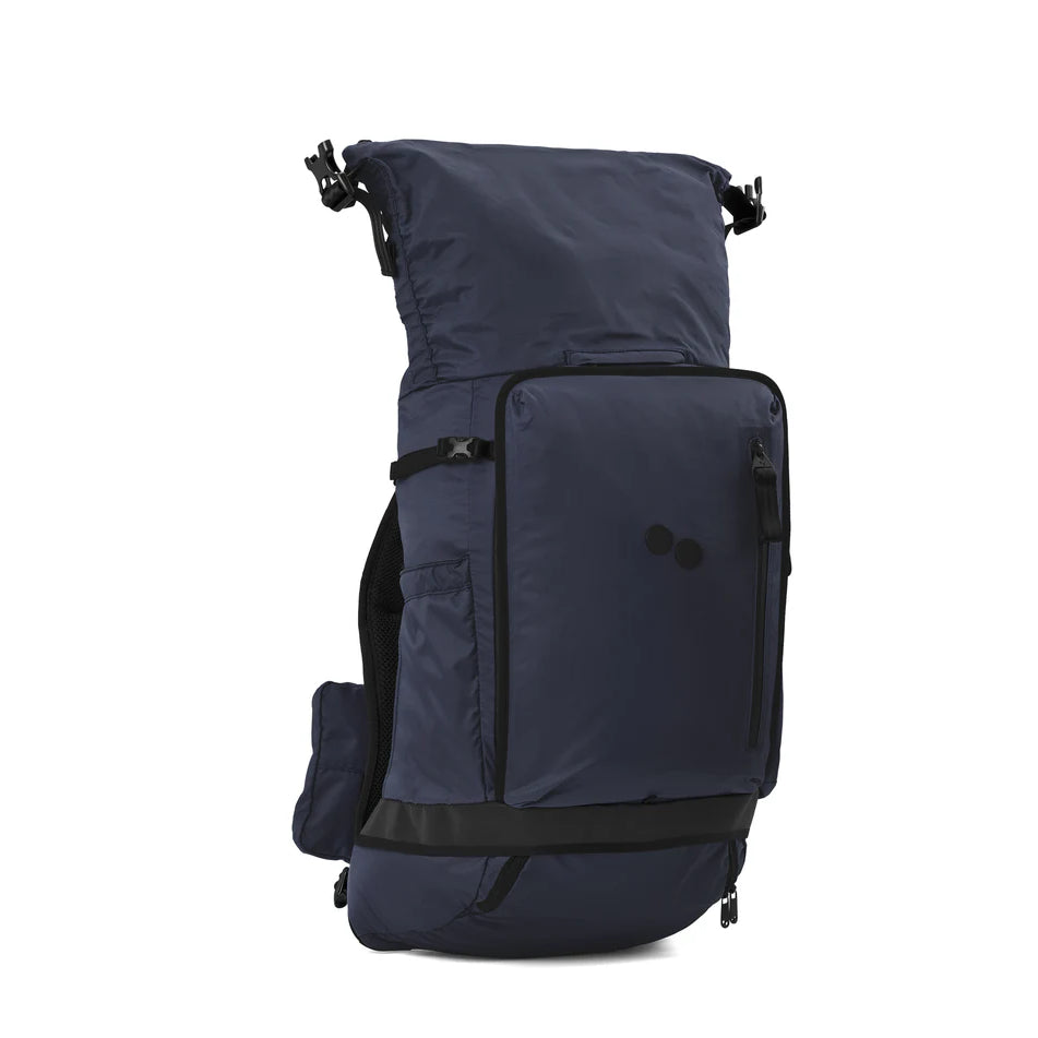 Ein marineblauer Rolltop-Rucksack mit mehreren Fächern, schwarzen Reißverschlüssen, verstellbaren Trägern und einer Reißverschlusstasche auf der Vorderseite, der aufrecht vor einem schlichten weißen Hintergrund steht.