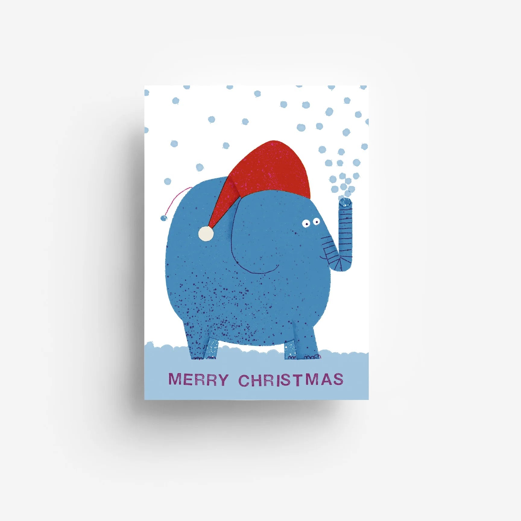 Ein blauer Cartoon-Elefant mit einer roten Weihnachtsmannmütze steht auf einem hellblauen Fleck und bläst Schnee aus seinem Rüssel. Der Text darunter lautet Frohe Weihnachten in lila Buchstaben auf blauem Hintergrund.