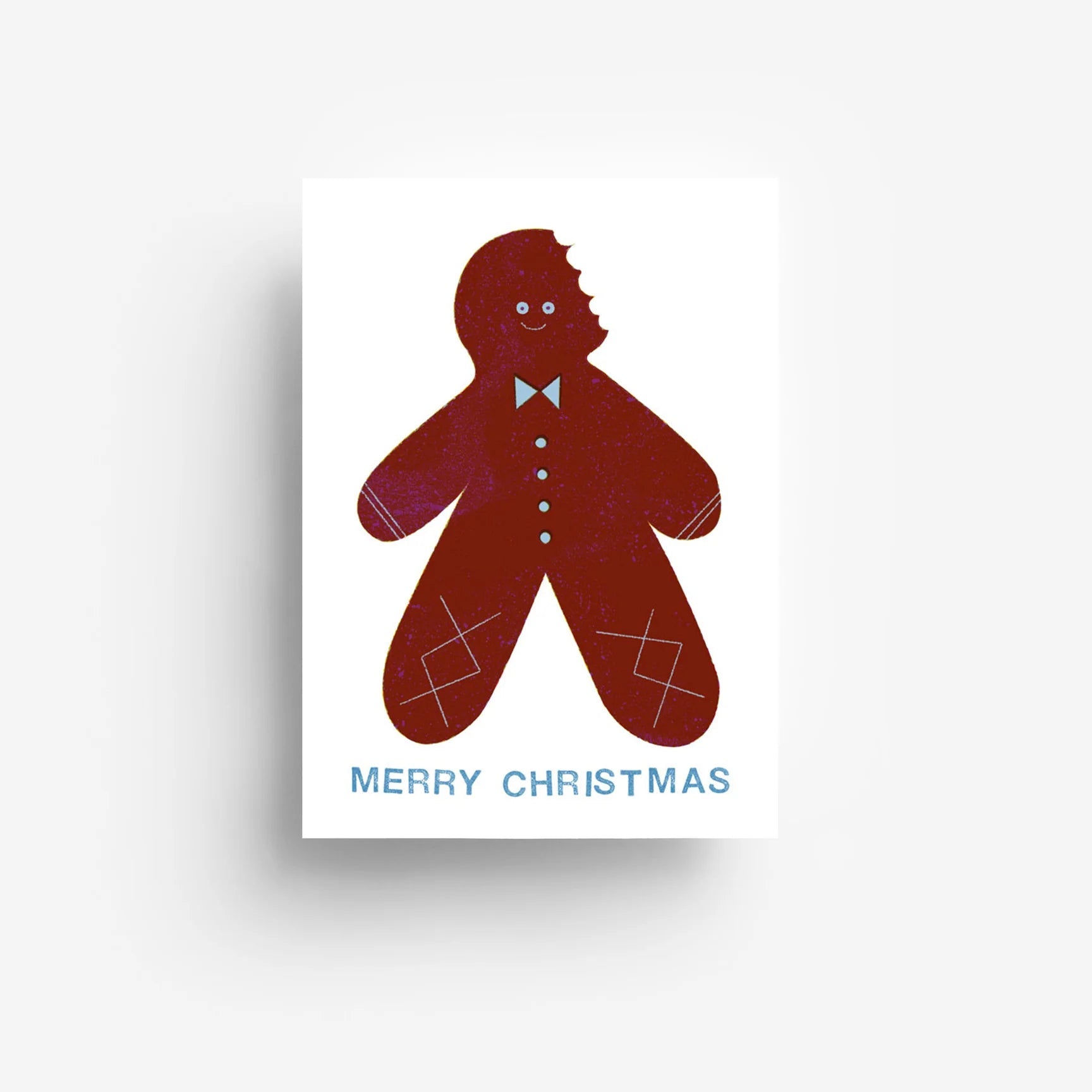 Eine Weihnachtskarte mit einem lächelnden Lebkuchenmann, dem ein Stück vom Kopf abgebissen wurde, der eine Fliege und Knöpfe trägt. Frohe Weihnachten steht in blauer Schrift unter dem Lebkuchenmann.