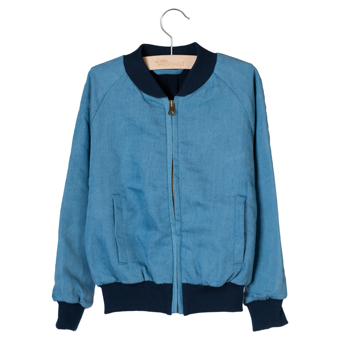 Eine blaue Bomberjacke mit schwarzen Rippenbündchen an Ärmeln, Kragen und Bund hängt auf einem Holzbügel vor einem weißen Hintergrund. Die Jacke hat einen Frontreißverschluss und zwei Taschen.