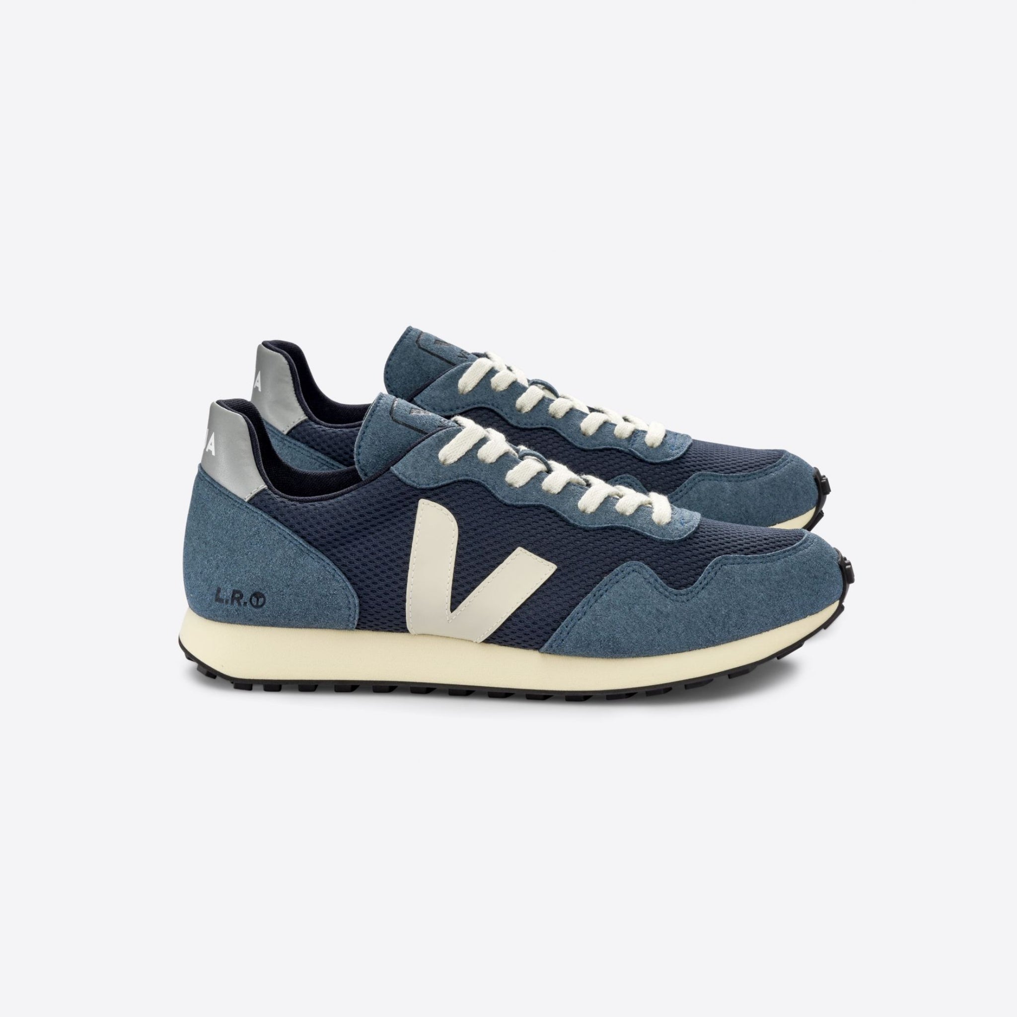 Blaue Sneaker mit cremefarbenem Logo, weißen Schnürsenkeln und schwarzer Sohle auf weißem Hintergrund.