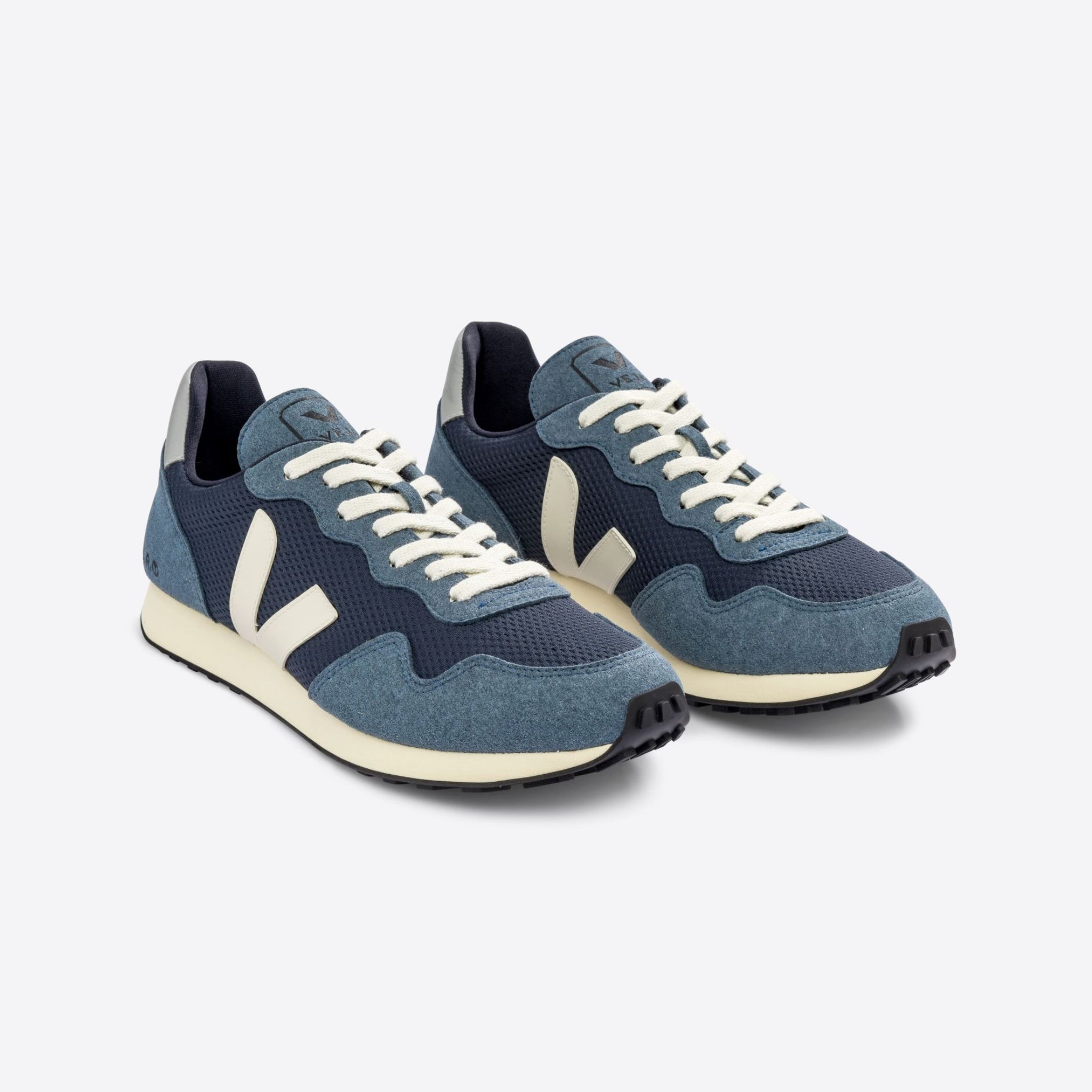 Blaue Sportschuhe mit weißen Logos und Schnürsenkeln auf weißem Hintergrund.