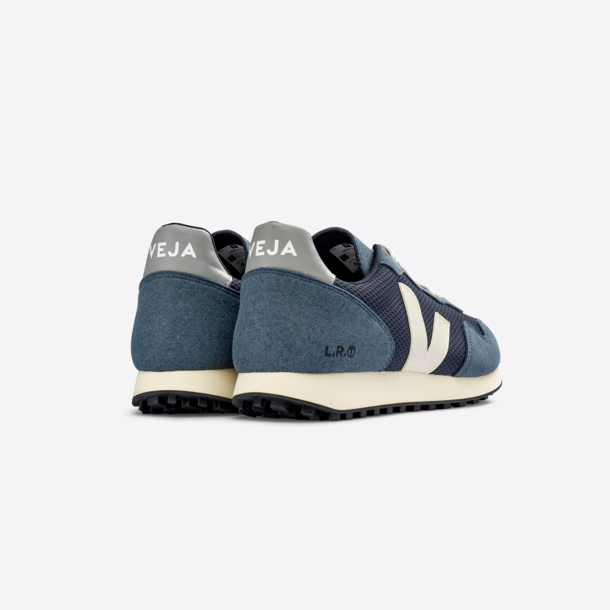 Blauer Sneaker von Veja mit hellgrauem Emblem, seitlicher Perspektive auf grauer Oberfläche.