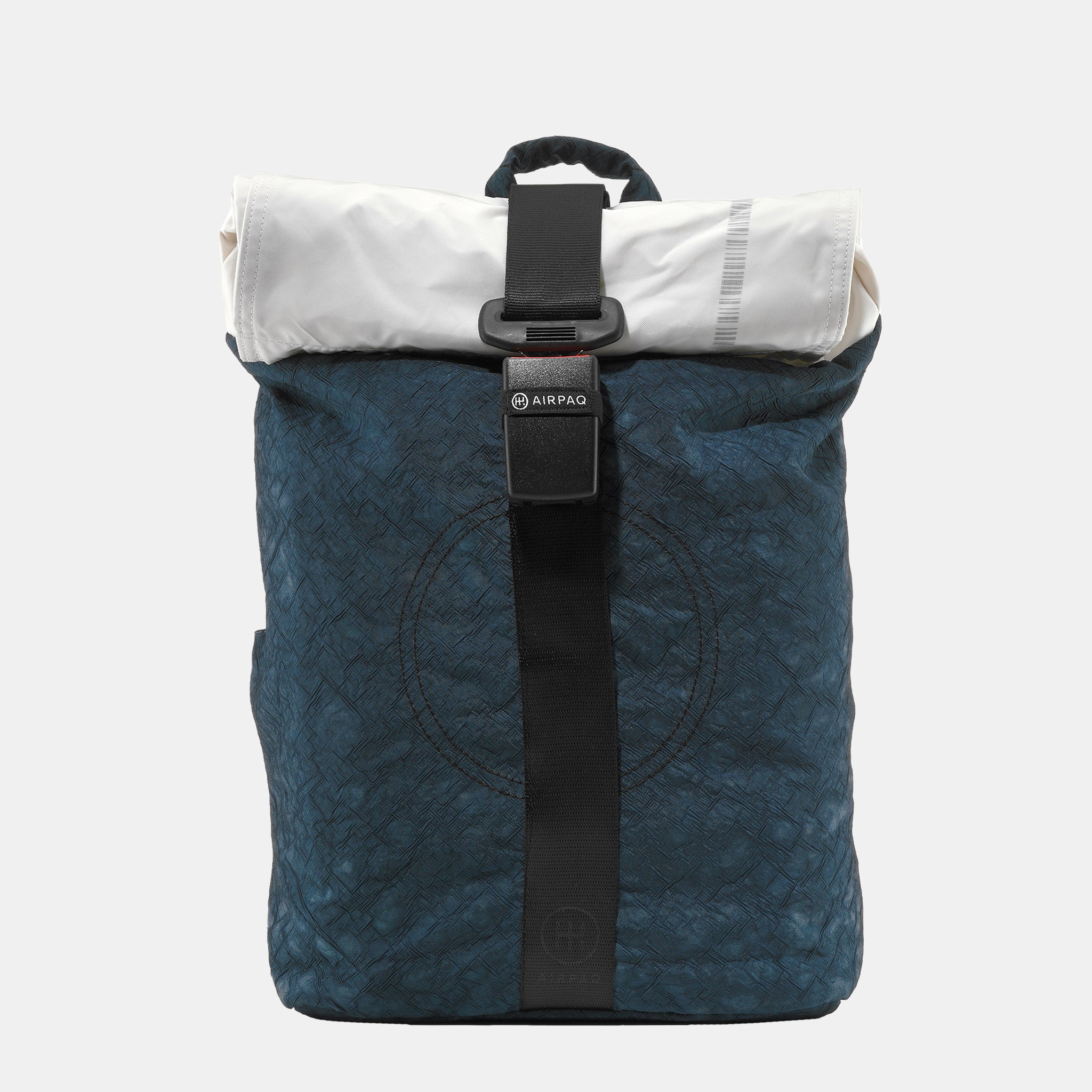 Ein blauer, strukturierter Rucksack mit einem schwarzen, vertikalen Riemen und einer Schnalle auf der Vorderseite, mit einem weißen Rollverschluss und einem kleinen Griff an der Oberseite, vor einem schlichten, hellen Hintergrund.