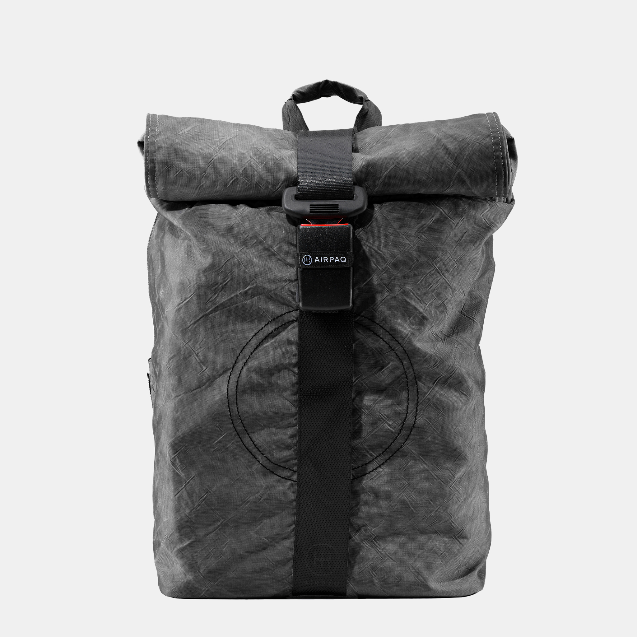 Ein schwarzer Rolltop-Rucksack aus strukturiertem, recyceltem Material mit Schnallenverschluss, sichtbaren Nähten und dem AIRPAQ-Logo auf dem vorderen Riemen vor einem schlichten weißen Hintergrund.
