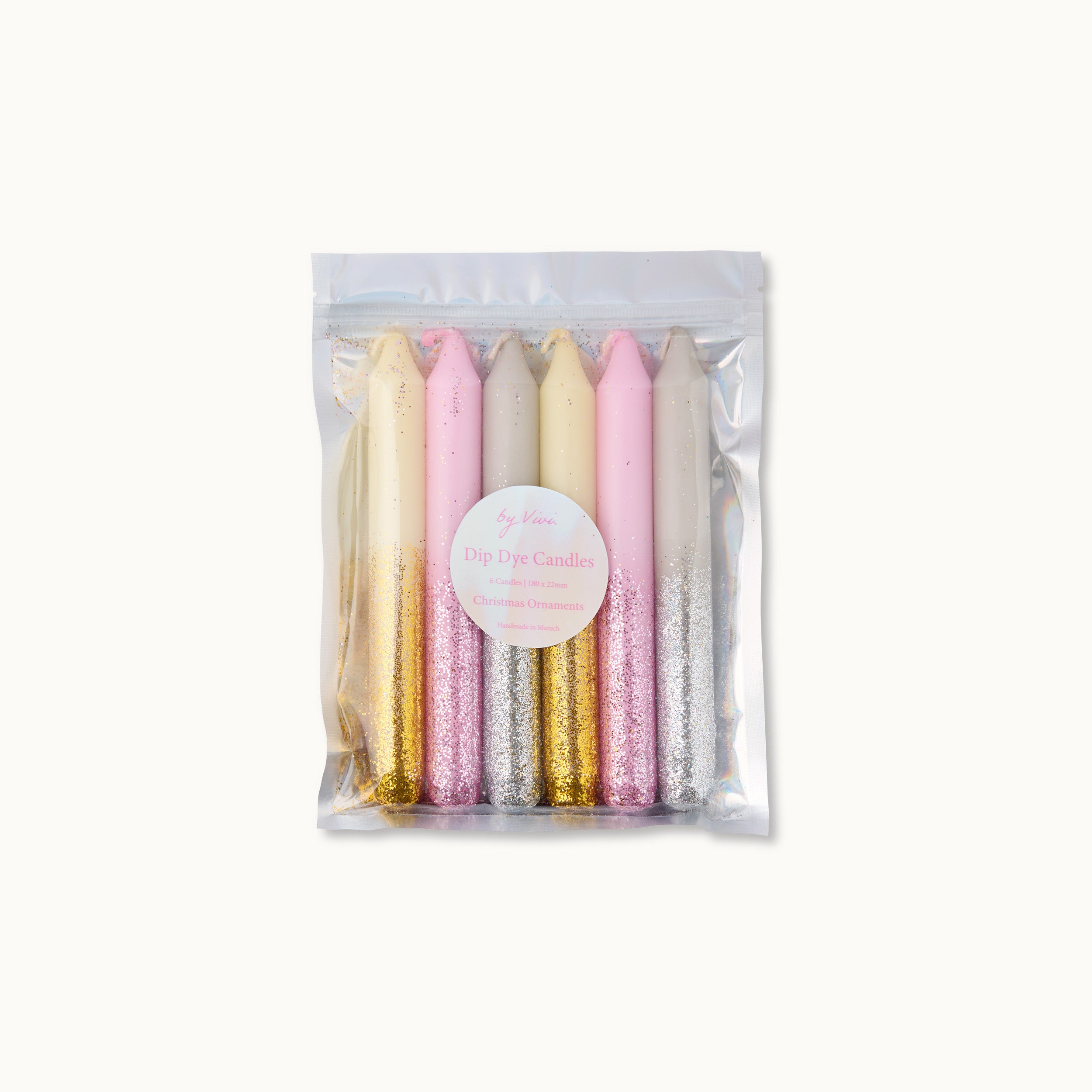 Ein durchsichtiger, wiederverschließbarer Beutel mit sechs im Tauchverfahren gefärbten Kerzen in Pastellfarben - Rosa, Weiß und Lavendel -, die jeweils eine glitzernde goldene oder silberne untere Hälfte haben. Auf dem Etikett steht "Dip Dye Candles" mit zusätzlichem Text darunter.