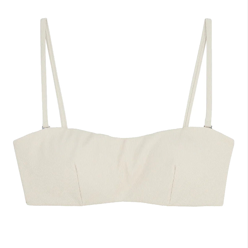 Ein cremefarbenes, geripptes Crop-Top mit dünnen Spaghetti-Trägern auf weißem Hintergrund.