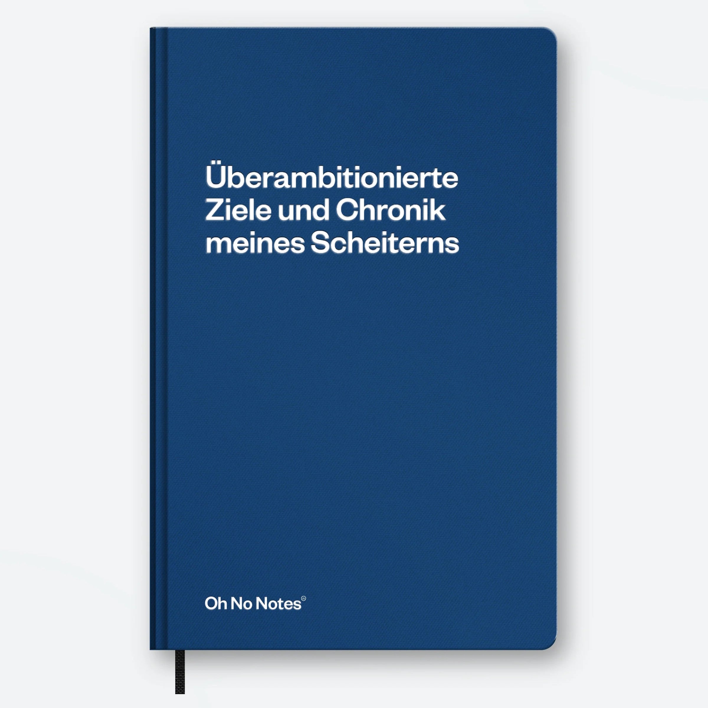 Ein blaues Notizbuch mit weißem Text auf Deutsch, der lautet: Überambitionierte Ziele und Chronik meines Scheiterns. Die Marke Oh No Notes ist in kleinen Buchstaben am unteren Rand aufgedruckt.