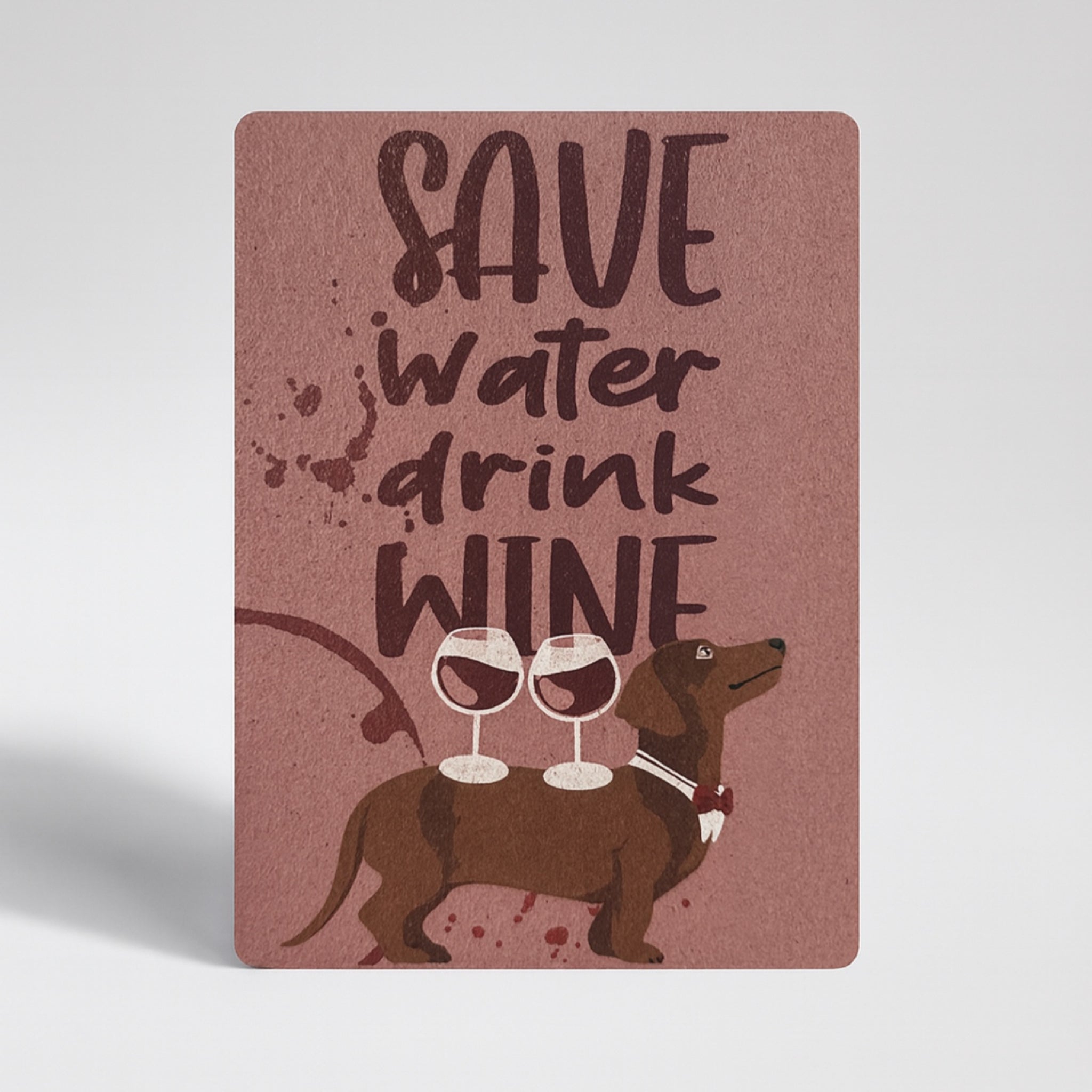 Eine Karte mit dem Text "Save water, drink wine" über zwei Weingläsern und einem braunen Dackel mit Fliege, alles auf einem kastanienbraunen Hintergrund mit Weinspritzern.