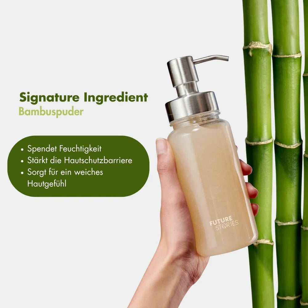 Eine Hand hält eine Pumpflasche mit der Aufschrift Future Stories, in der sich eine gelbe Flüssigkeit befindet. Daneben sind grüne Bambushalme und ein deutscher Text zu sehen, der Bambuspulver als wichtigen Inhaltsstoff für die Feuchtigkeitsversorgung und den Schutz der Haut hervorhebt.