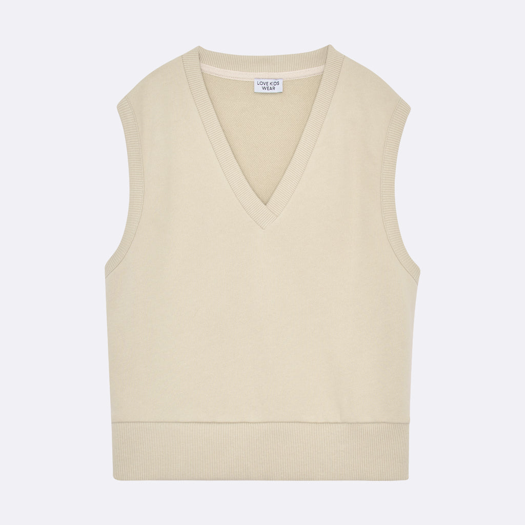 Eine ärmellose, hellbeige Strickweste mit V-Ausschnitt und gerippten Rändern, flach auf weißem Grund gelegt.