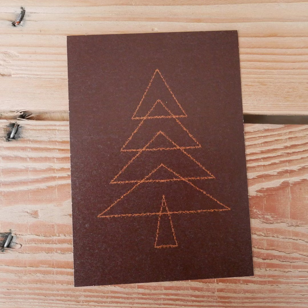Karte mit einem stilisierten Weihnachtsbaum aus orangefarbenen Linien auf dunkelbraunem Hintergrund, liegt auf Holz.