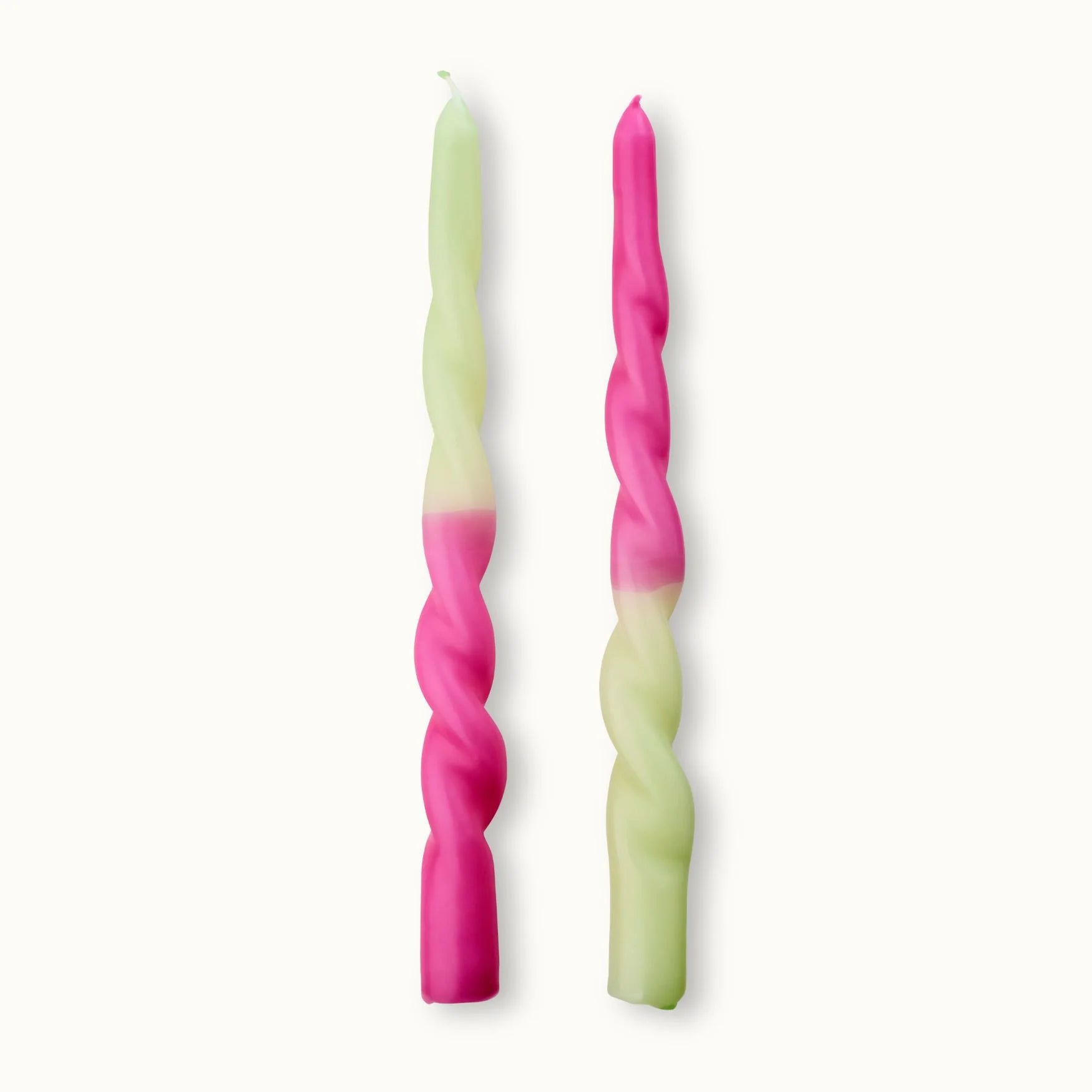 Zwei gedrehte Kerzen, jeweils halb rosa und halb hellgrün, stehen aufrecht auf einem schlichten weißen Hintergrund. Der Farbübergang befindet sich bei jeder Kerze auf einer anderen Höhe.