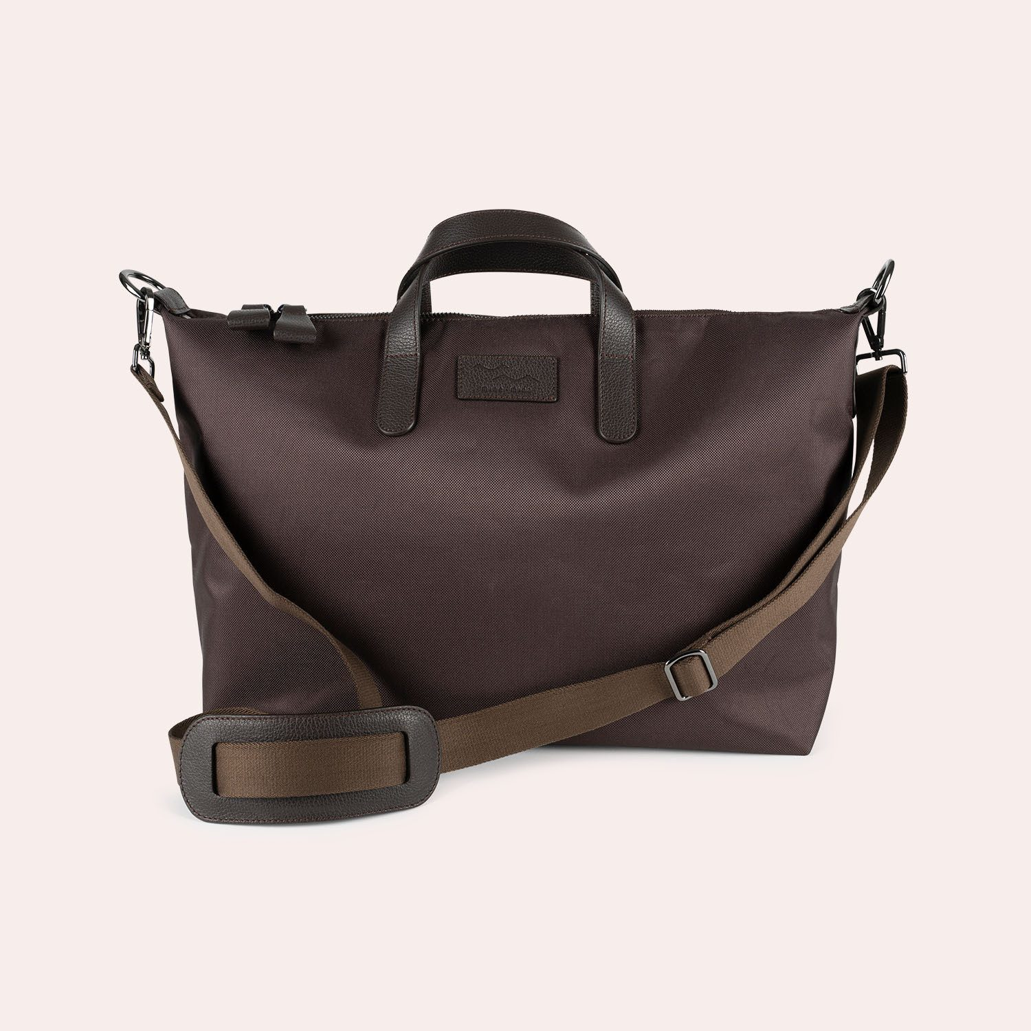Eine dunkelbraune Tragetasche mit schwarzen Ledergriffen, einem passenden abnehmbaren Schulterriemen und einem Reißverschluss oben, dargestellt vor einem hellen Hintergrund.