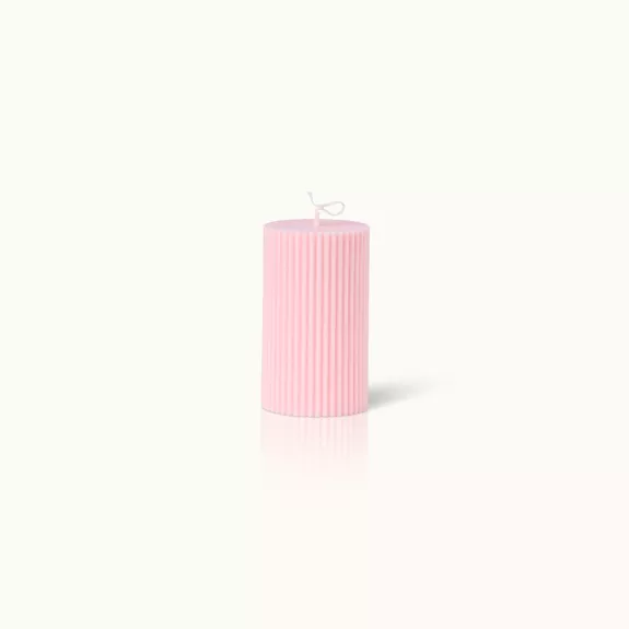 Eine rosa, gerippte Kerze mit Docht, auf hellem Hintergrund.