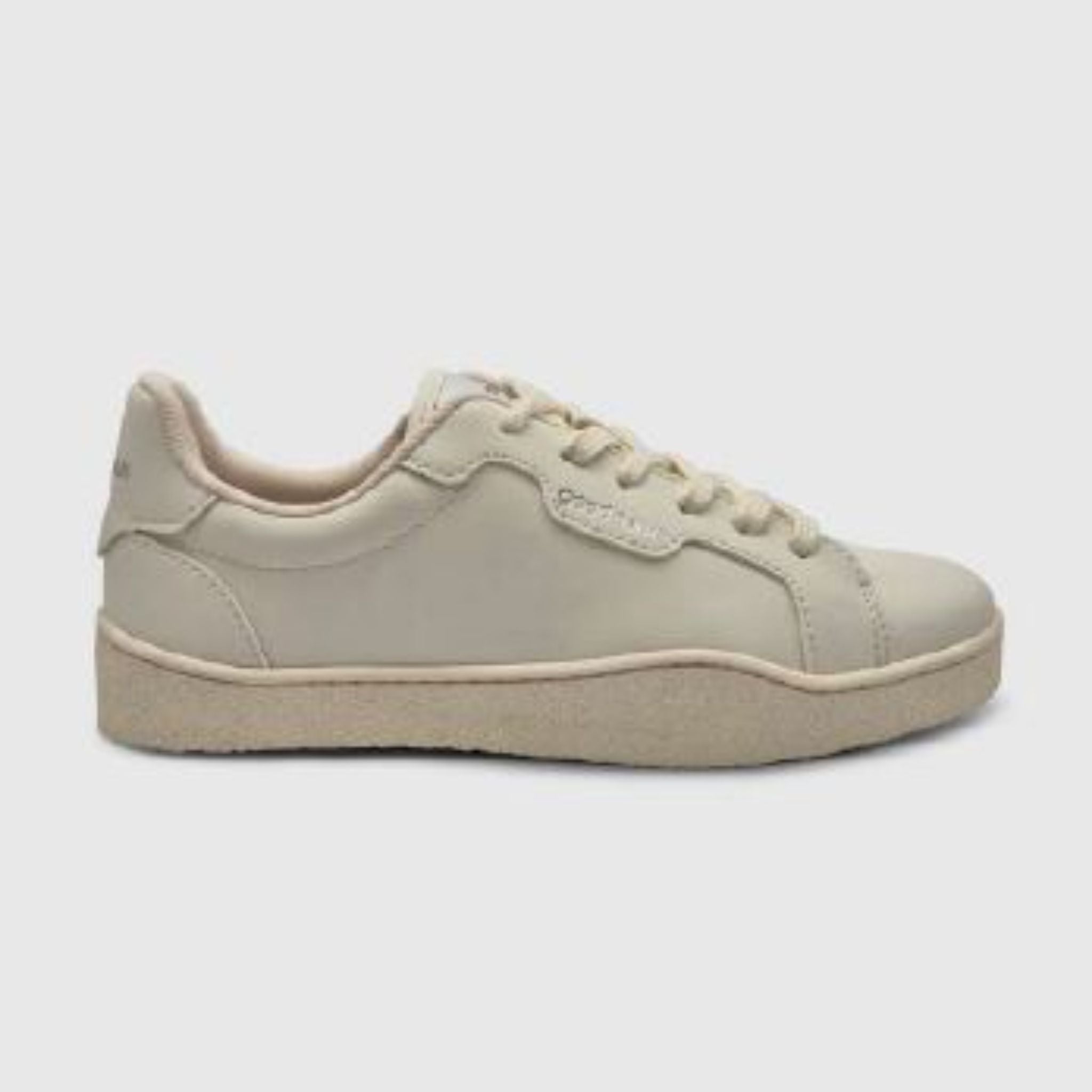 Ein beiger Freizeit-Sneaker mit strukturierter Sohle, Schnürung und tiefem Profil auf einfarbig hellgrauem Hintergrund.
