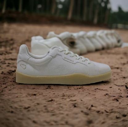 Eine Reihe weißer Sportschuhe steht auf einem sandigen Untergrund im Freien.