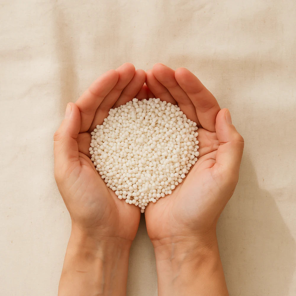 Zwei Hände halten einen Haufen kleiner, runder weißer Tapioka-Perlen vor einem hellbeigen Hintergrund.