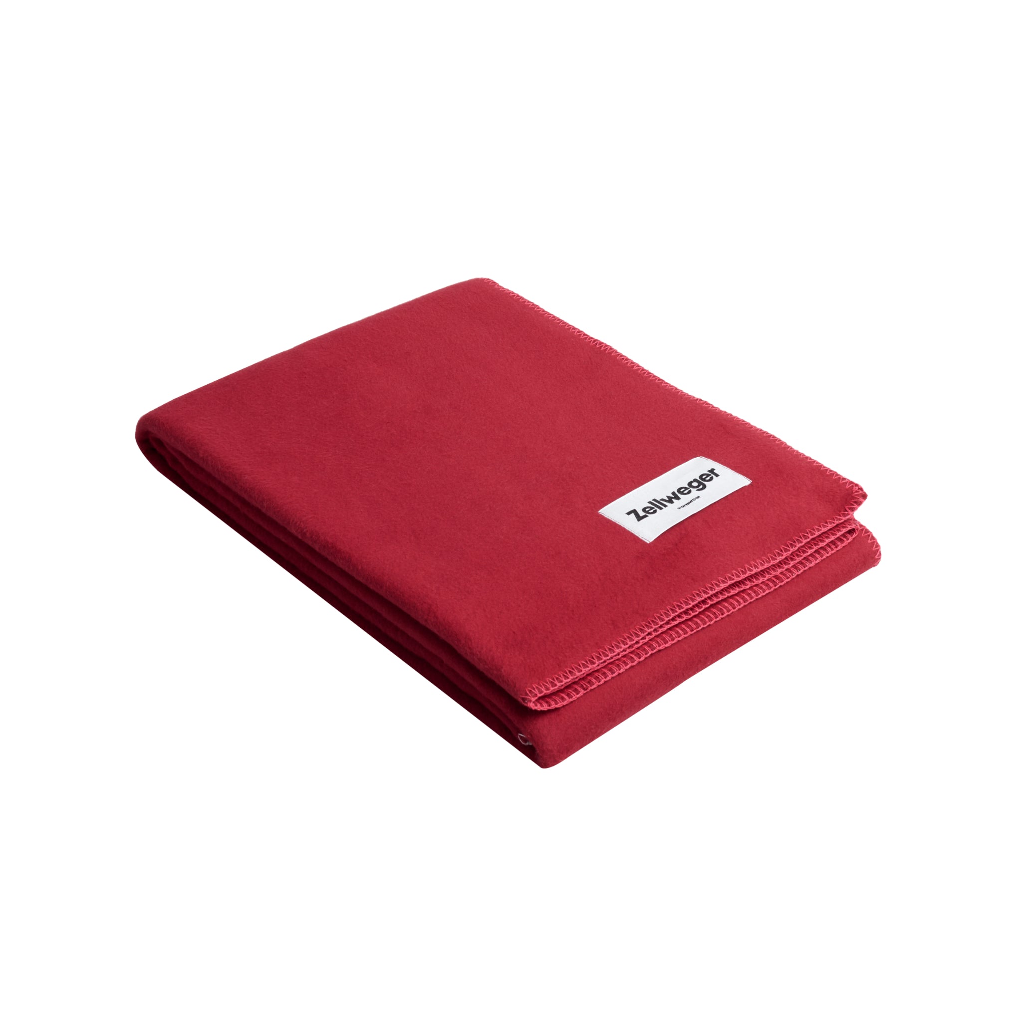 Gefaltete rote Decke mit einem weißen Etikett auf der Oberfläche, auf hellem Hintergrund.