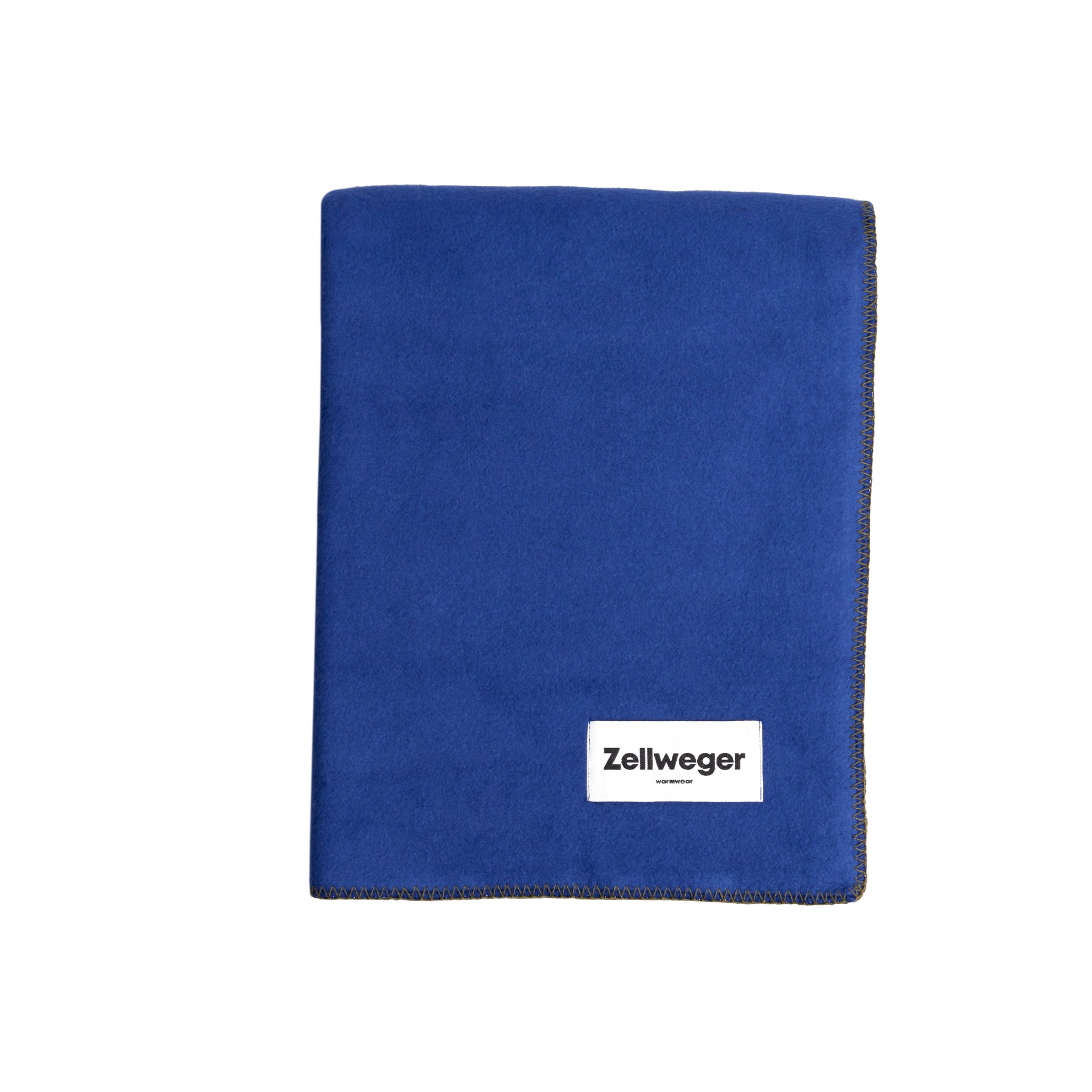 Blaue Fleecedecke mit einem weißen Etikett, auf dem "Zellweger" steht, unten rechts auf der Decke.