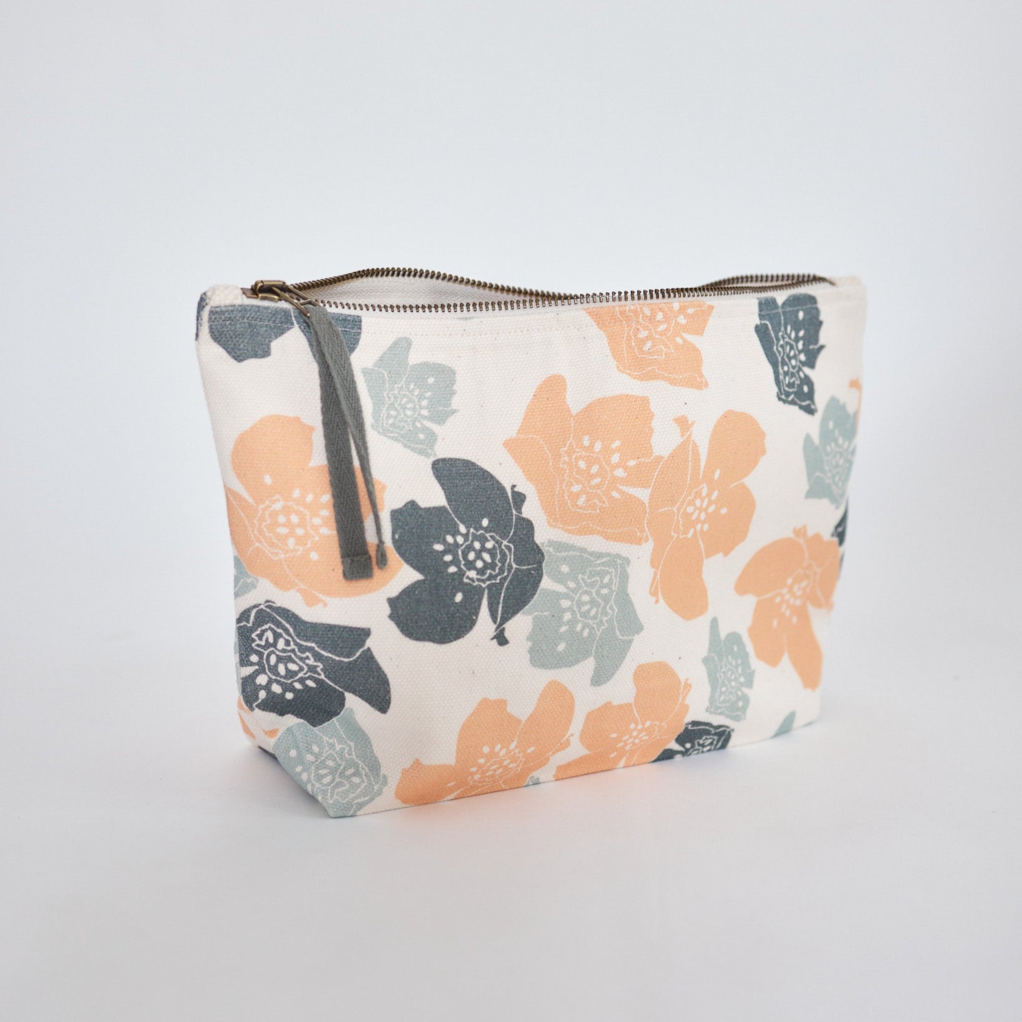 Kosmetiktasche mit Reißverschluss und floralem Muster in Orange, Grau und Blau auf hellem Hintergrund.