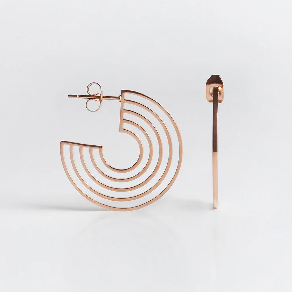 Ein Paar Ohrringe aus Roségold mit einem offenen, geometrischen, konzentrischen Muster. Ein Ohrring ist von vorne gezeigt, was das kreisförmige Muster zeigt, der andere von der Seite, was sein dünnes Profil zeigt.