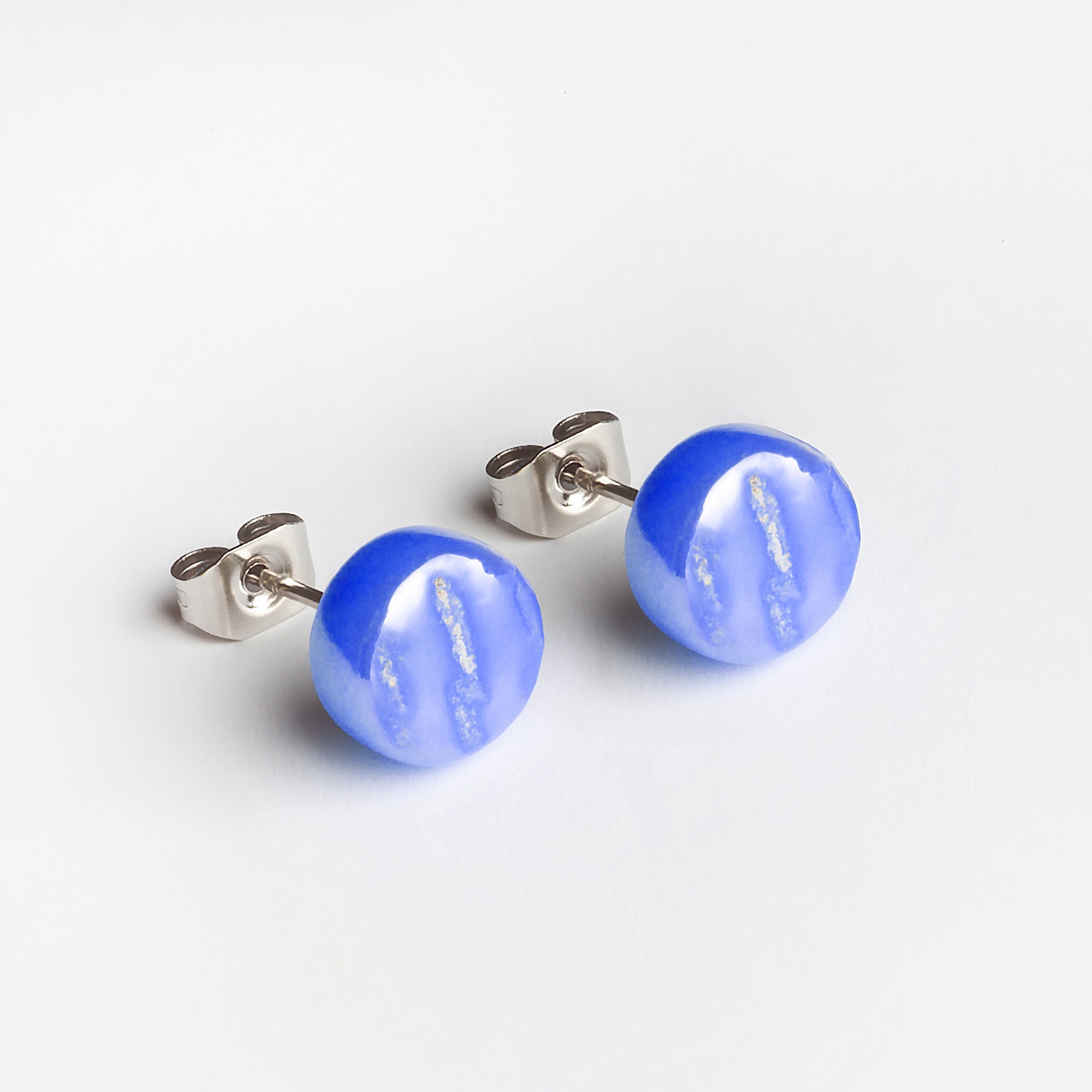 Ein Paar runder, blauer Ohrstecker mit glänzender Oberfläche und subtilen weißen Streifenmustern, befestigt an silbernen Metallstiften und Schmetterlingsverschlüssen, dargestellt auf weißem Hintergrund.
