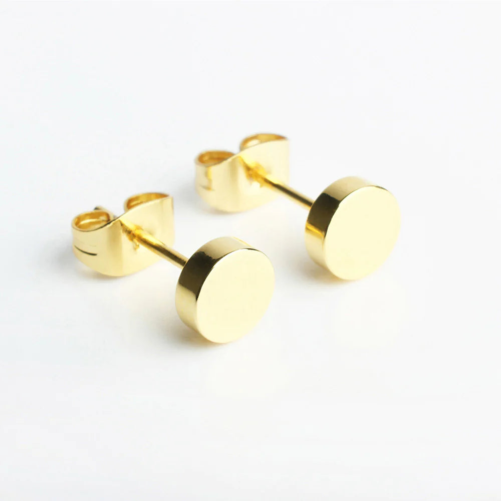 Ein Paar schlichte, runde goldene Ohrstecker mit flacher, polierter, runder Vorderseite und Schmetterlingsrückseite auf weißem Hintergrund.