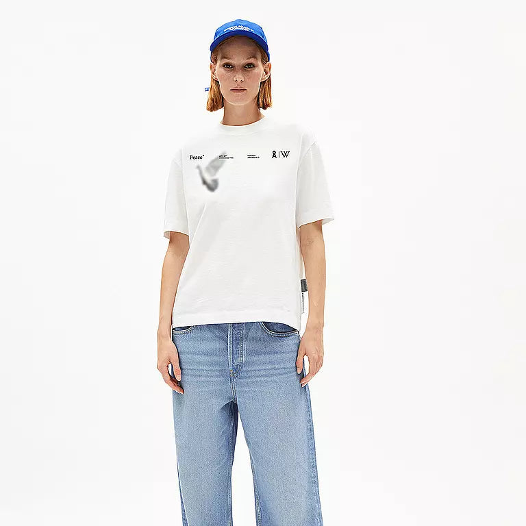 Eine Person, die eine blaue Kappe, ein weißes T-Shirt mit schwarzem Text und Grafiken, eine weite hellblaue Jeans und schwarz-blaue Sandalen trägt, steht mit dem Gesicht nach vorne vor einem schlichten weißen Hintergrund.