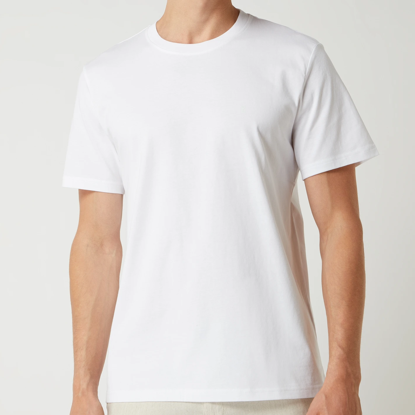 Person trägt ein weißes T-Shirt vor einem neutralen Hintergrund.