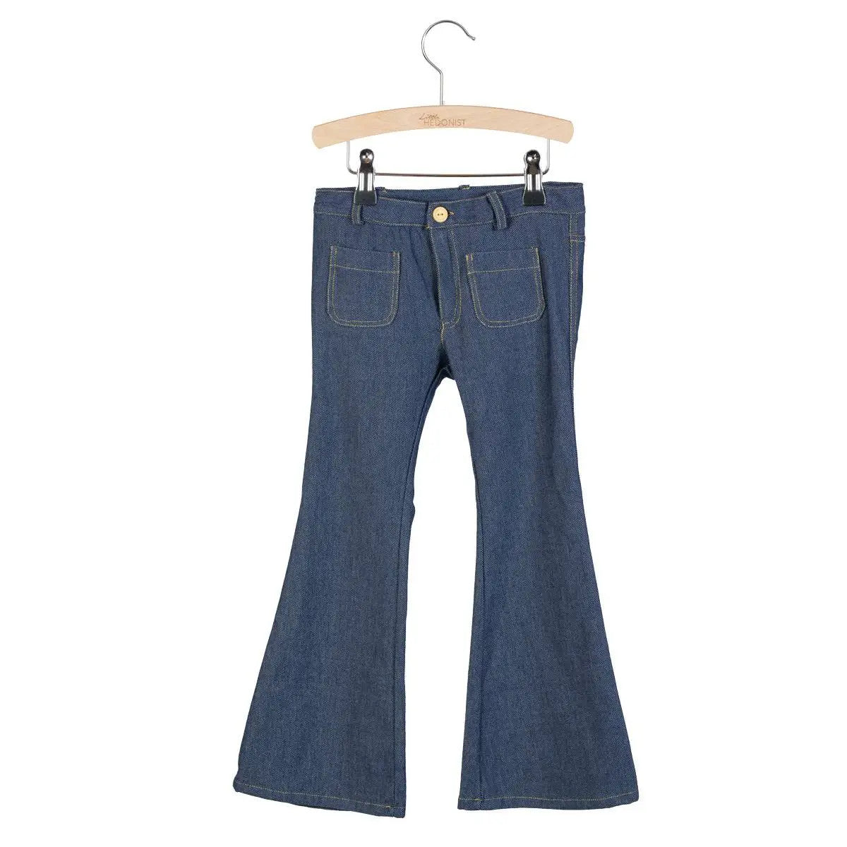 Ein Paar Jeans aus blauem Denim mit Glockentaschen, die auf einem Holzbügel vor einem weißen Hintergrund hängen.