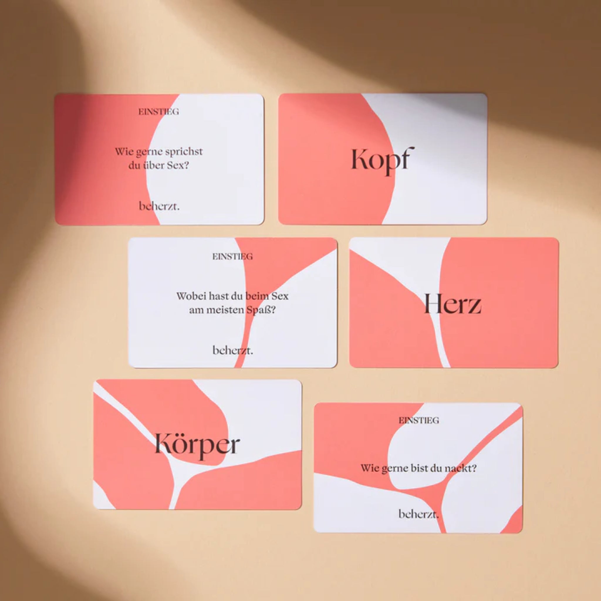 Sechs Karten mit Fragen und Worten wie "Kopf", "Herz" und "Körper" auf einem beigen Hintergrund.