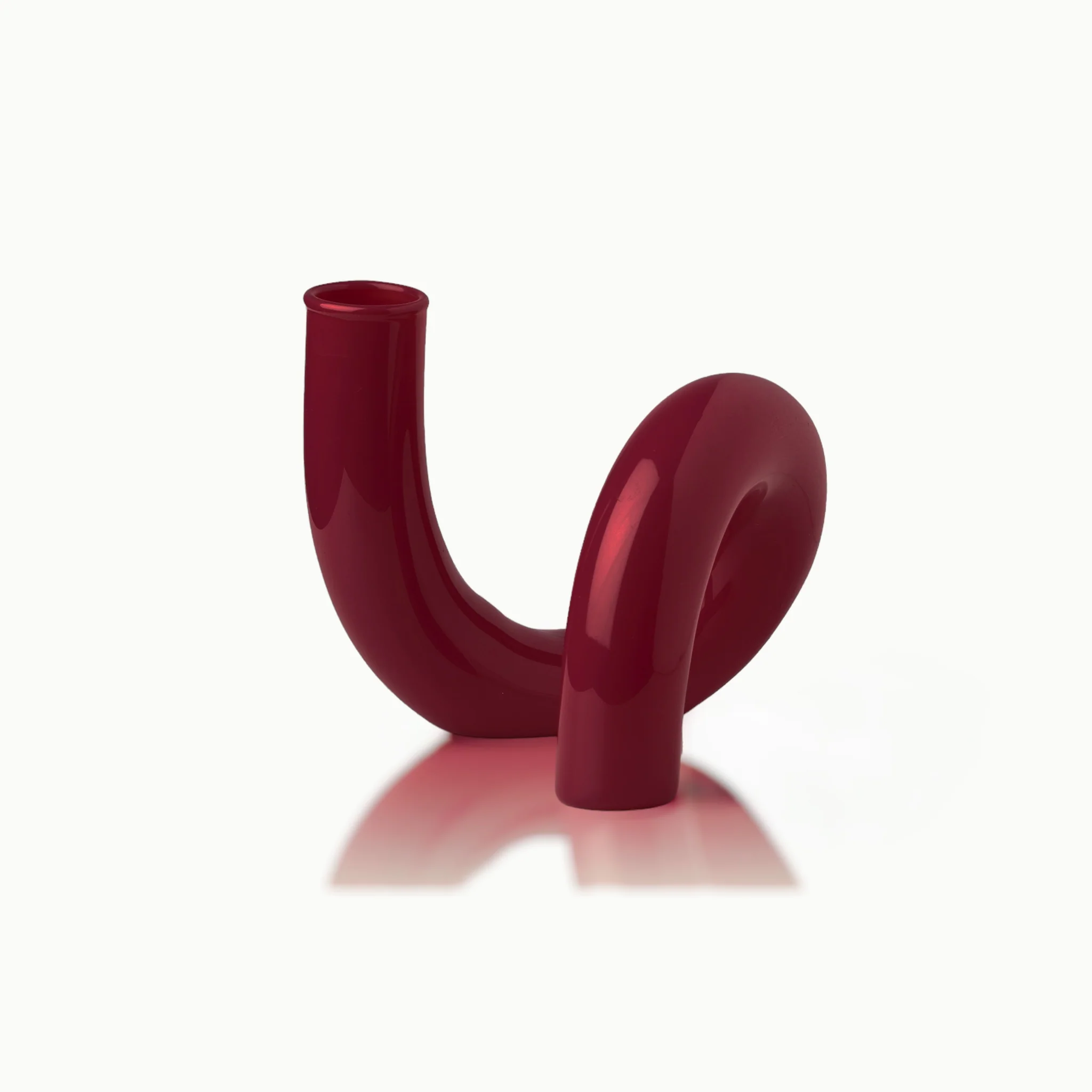 Rote, glänzende Vase in geschwungener Form auf weißem Hintergrund.