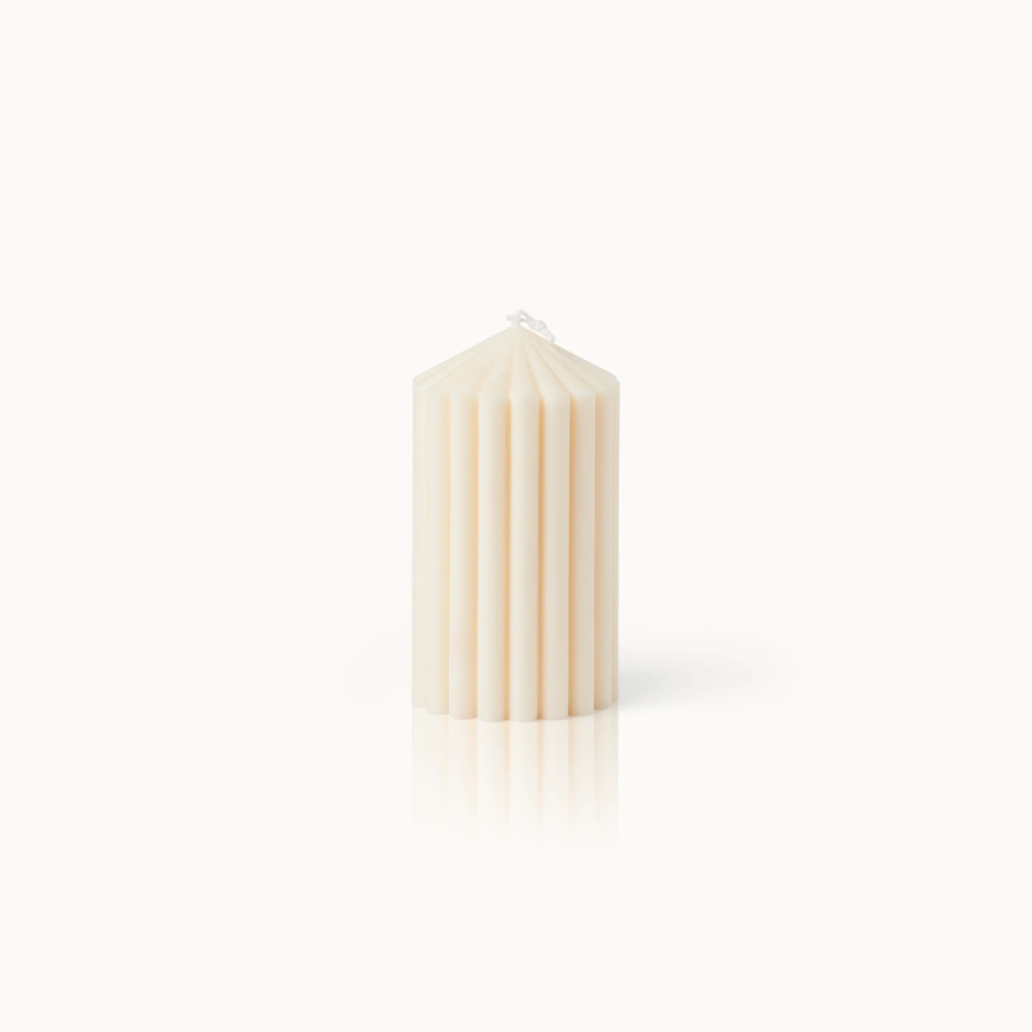 Beige geriffelte Kerze vor einem hellen Hintergrund.
