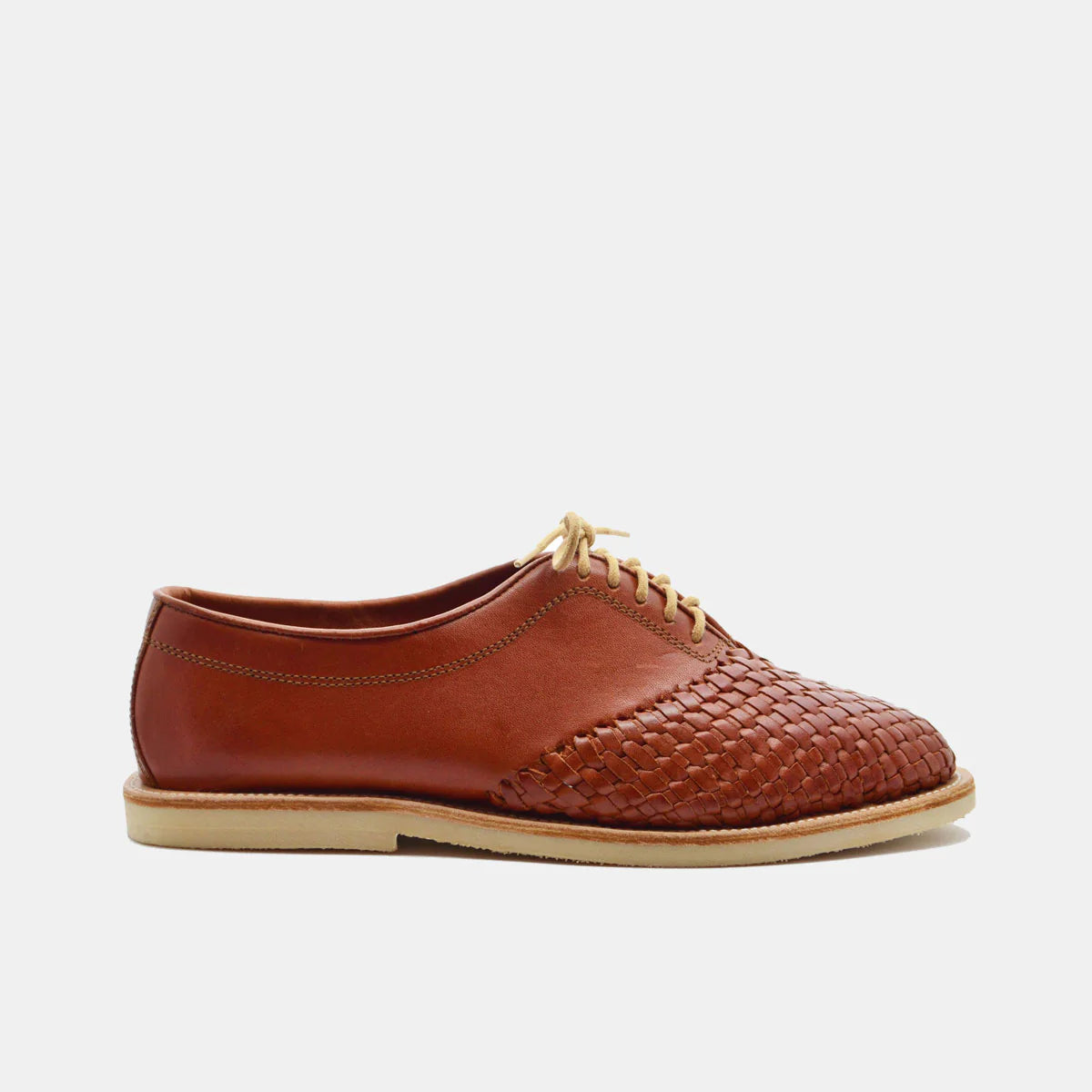 Ein brauner Lederschuh mit einem gewebten Vorderteil, beigen Schnürsenkeln und einer hellen Sohle, dargestellt im Seitenprofil auf einem einfarbig weißen Hintergrund.