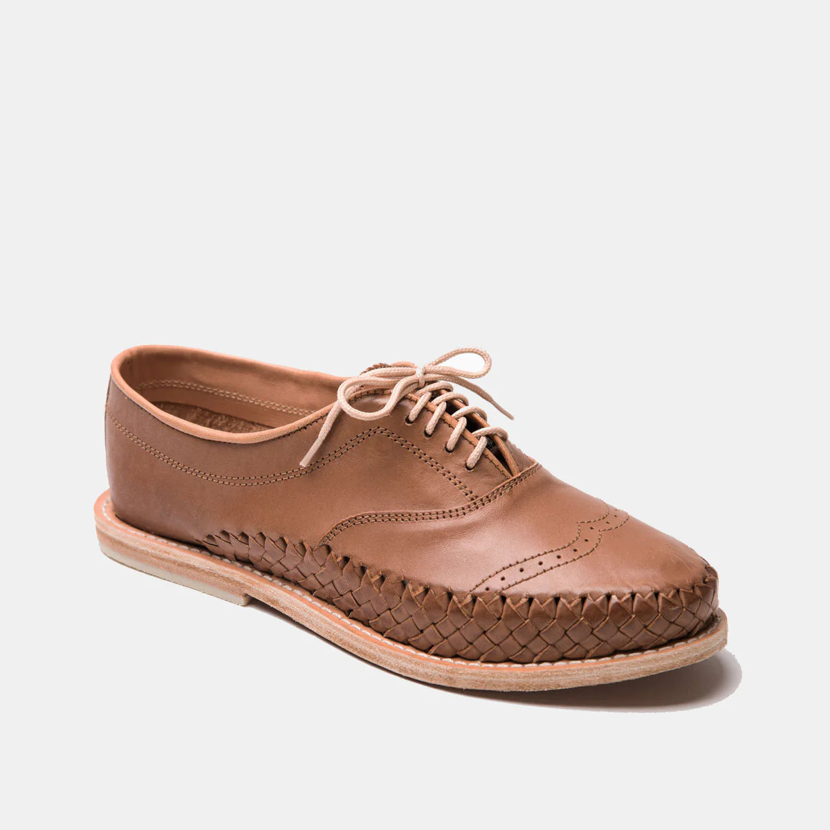 Ein einzelner brauner Lederschnürschuh mit einem gewebten Muster an den Seiten, Ziernähten an der Spitze und einer hellen Sohle, dargestellt auf einem einfarbig weißen Hintergrund.