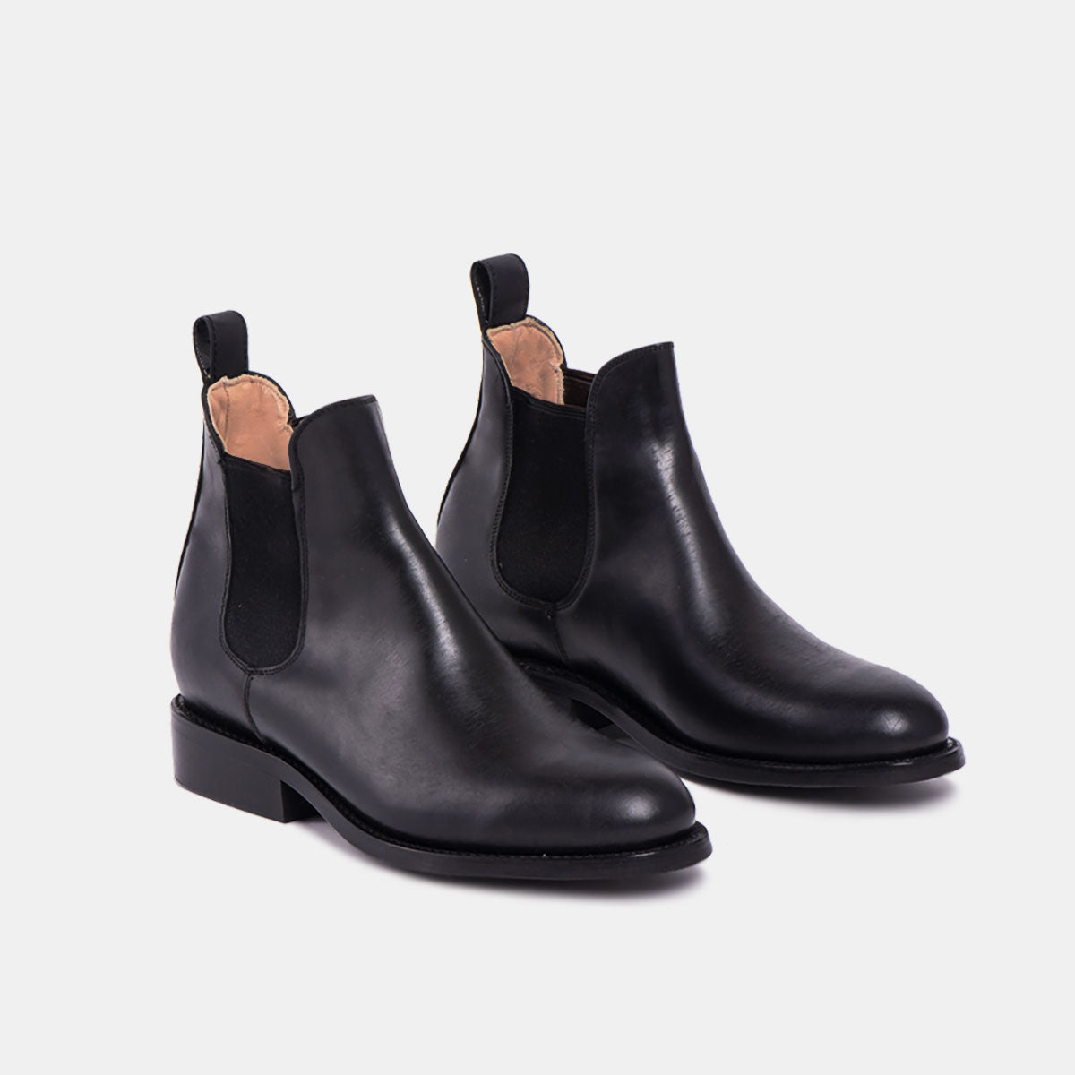 Ein Paar schwarze Chelsea-Stiefel aus Leder mit elastischen Seiteneinsätzen, Zuglaschen hinten und niedrigen Absätzen, dargestellt auf einem hellen Hintergrund.
