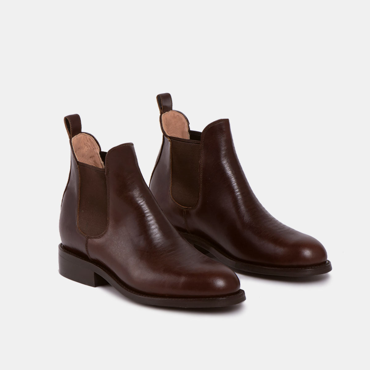 Ein Paar dunkelbraune Chelsea-Stiefel aus Leder mit elastischen Seitenteilen und Zuglaschen an der Rückseite, dargestellt auf weißem Hintergrund.