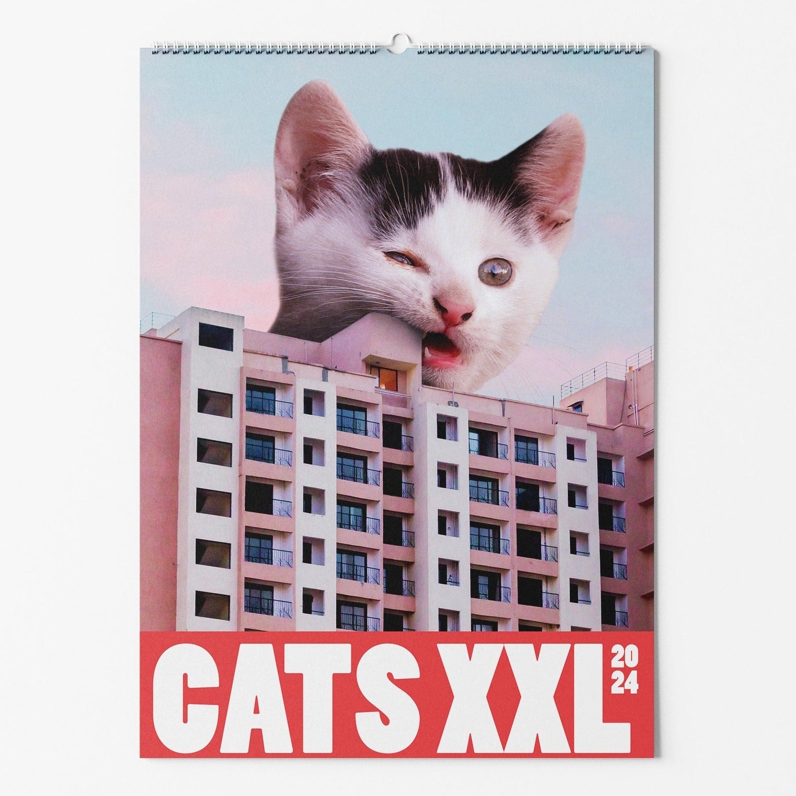Kalender-Cover mit riesiger Katze, die durch ein Gebäude schaut, und der Aufschrift "CATS XXL 2024" auf rotem Hintergrund.