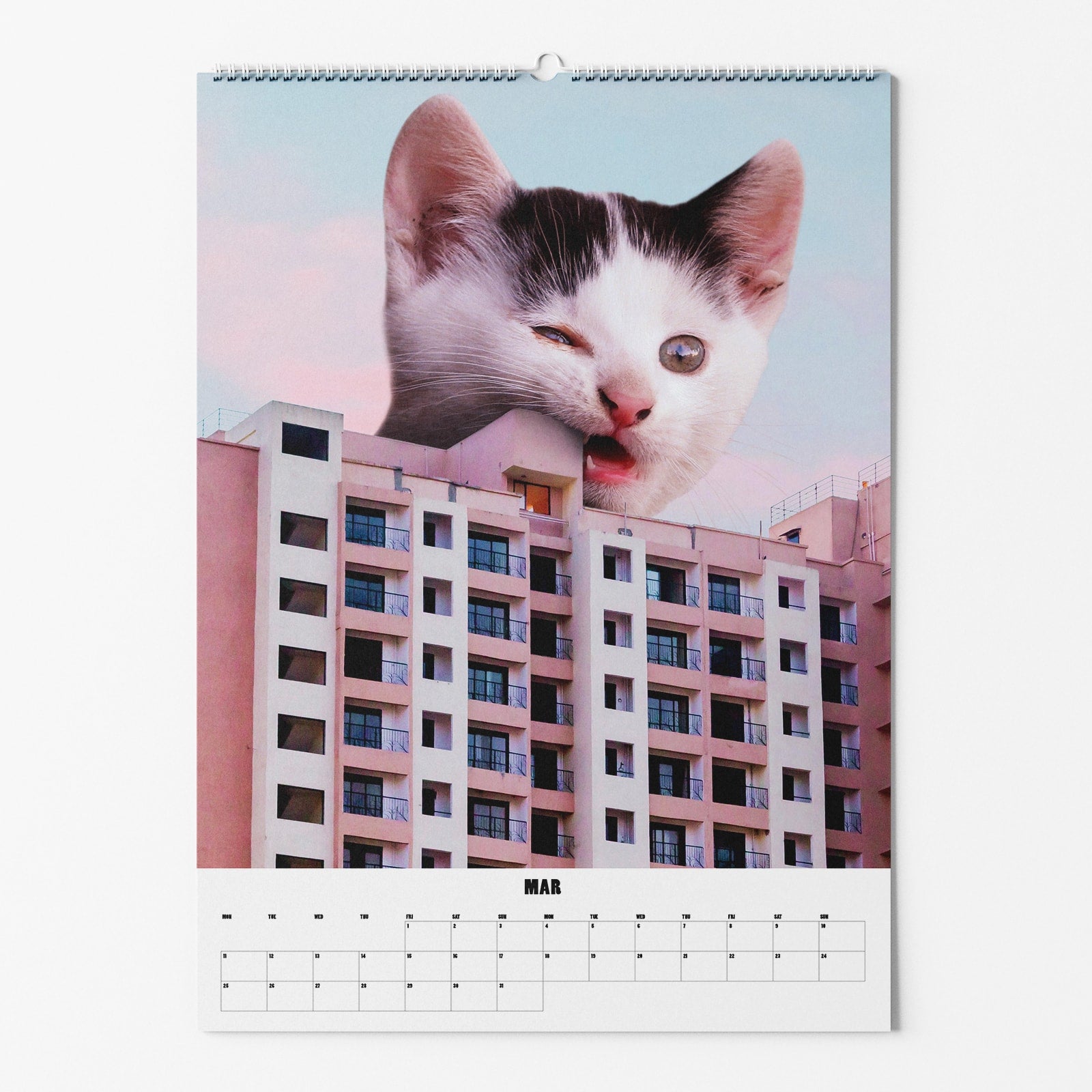 Kalenderbild mit einer riesigen Katze, deren Kopf hinter einem Hochhaus hervorragt, mit dem Monat März unten.